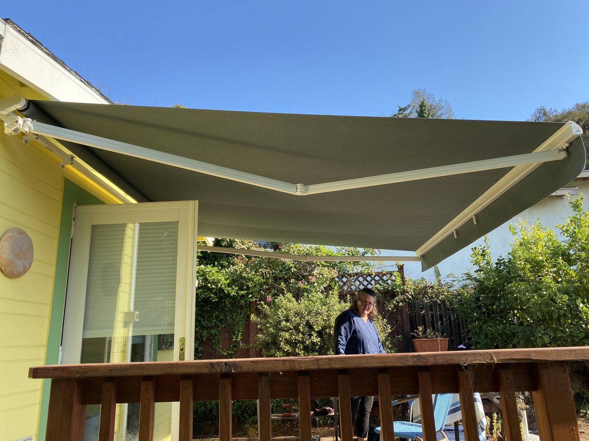 A man is standing on a deck under an awning.