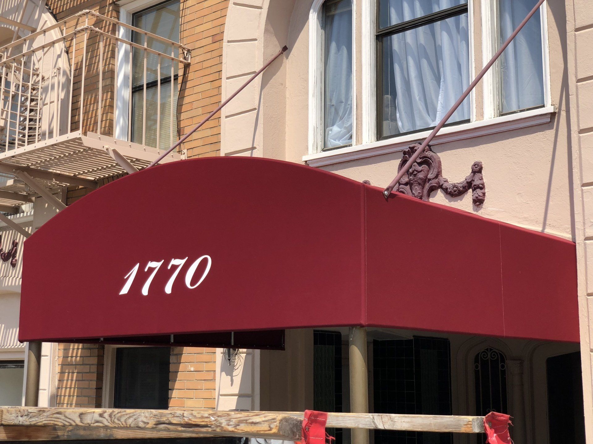 A red awning is hanging from the side of a building.