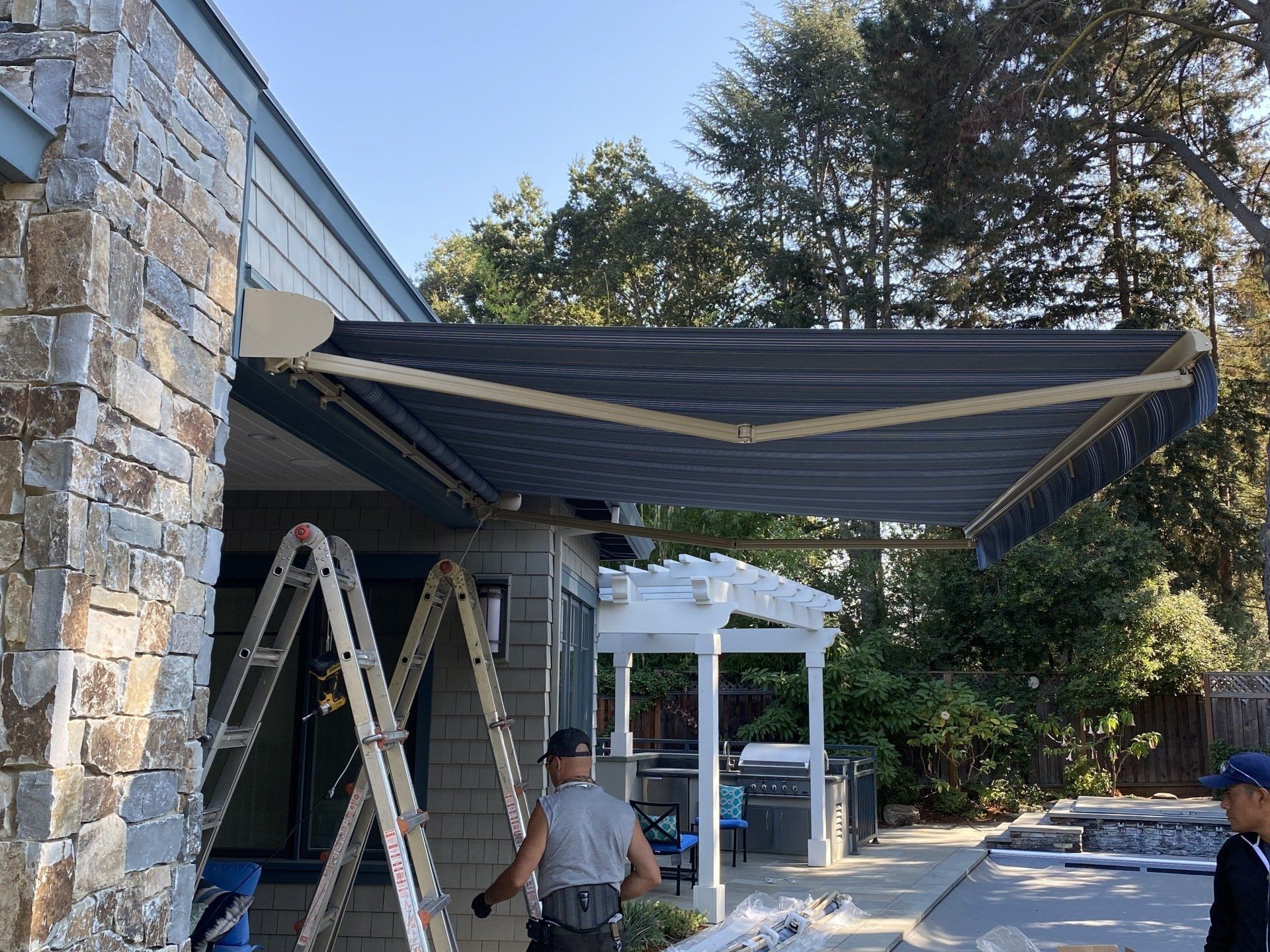 A man is working on an awning on the side of a house.