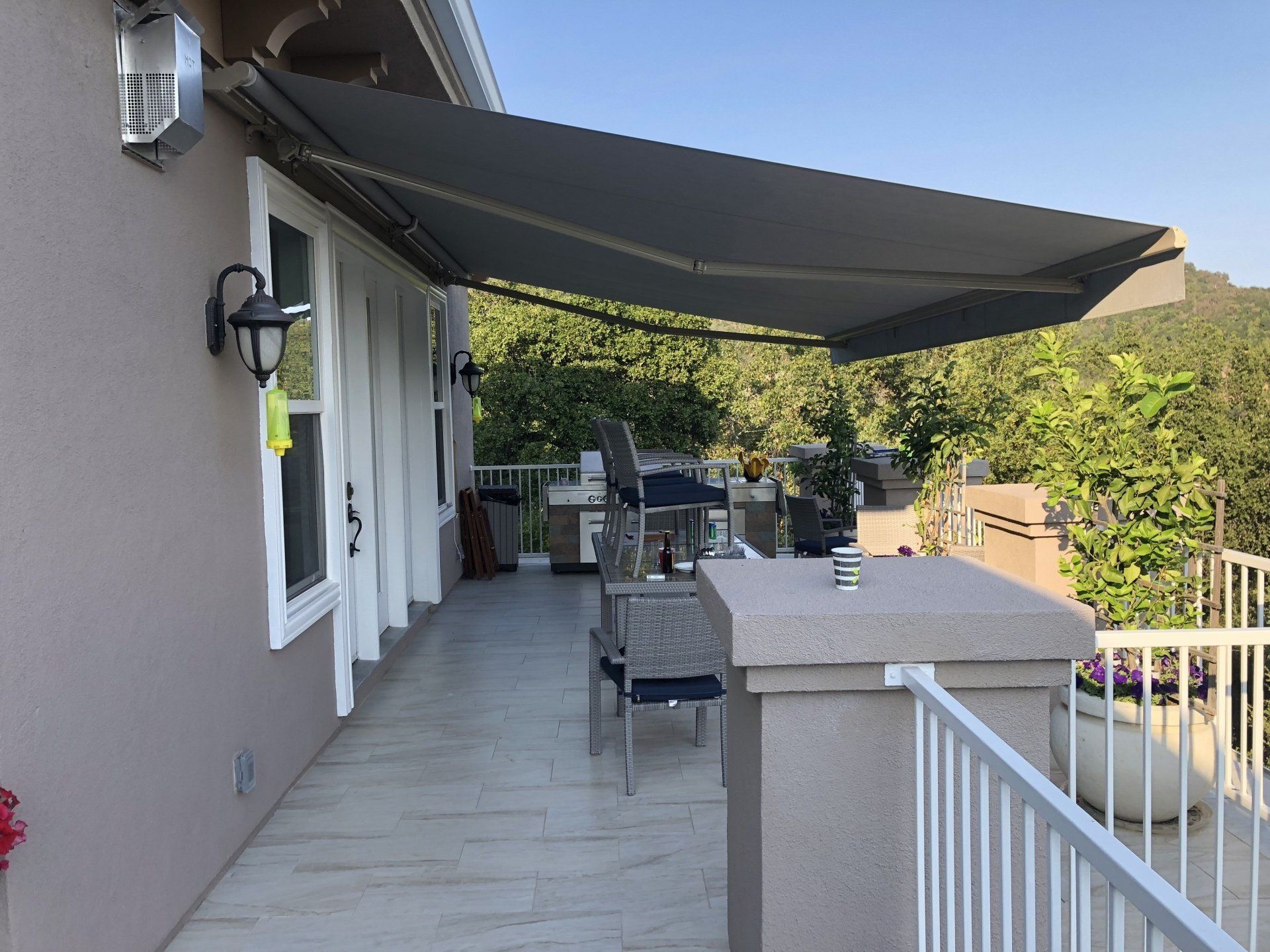A balcony with a large awning over it and a grill.