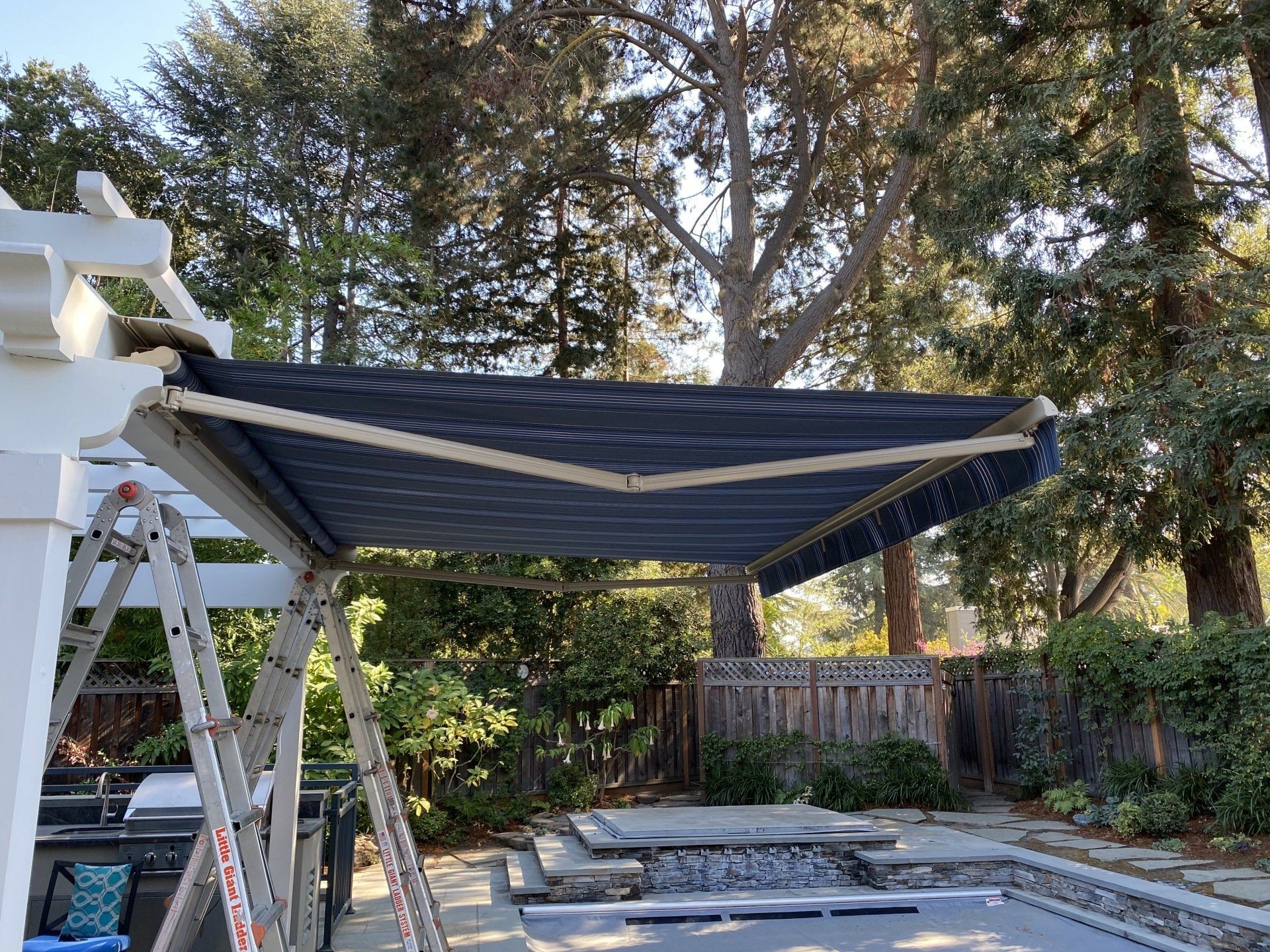 A blue awning is sitting on top of a white pergola.