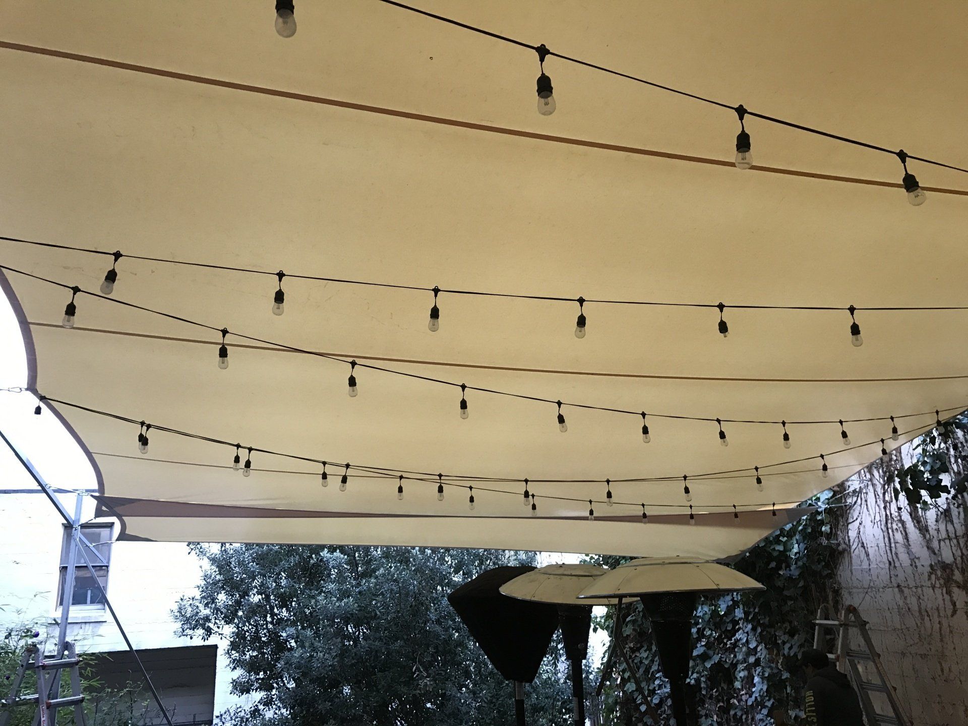 A large white umbrella is hanging from a string of lights
