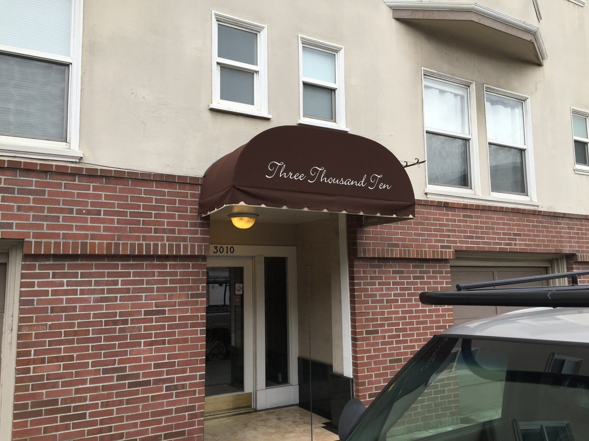 A brick building with a brown awning over the entrance