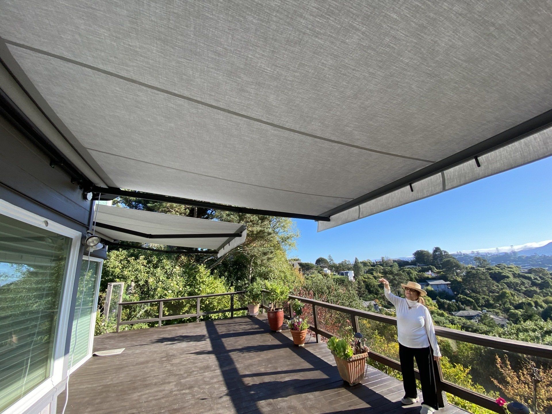 A woman is standing on a balcony with an awning over it.