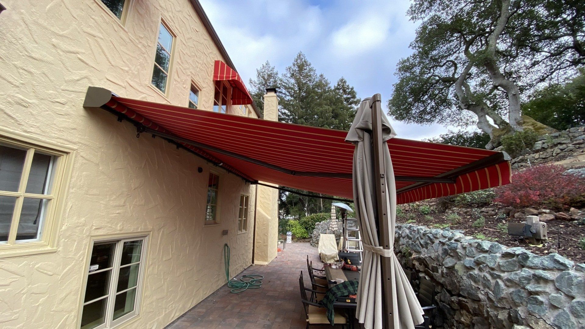 A house with a red awning and umbrellas on the side of it.