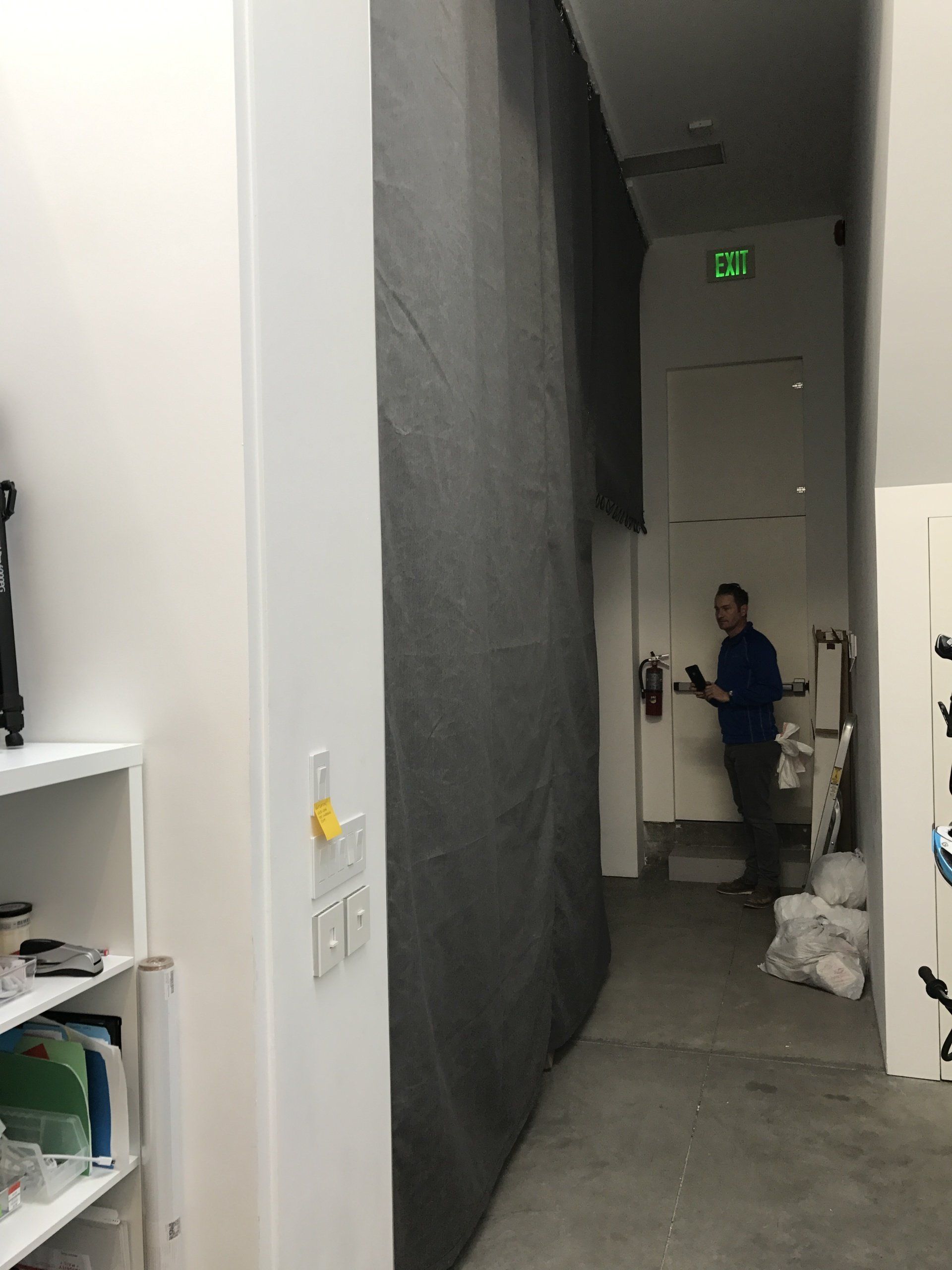 A man is standing in a hallway next to a wall.