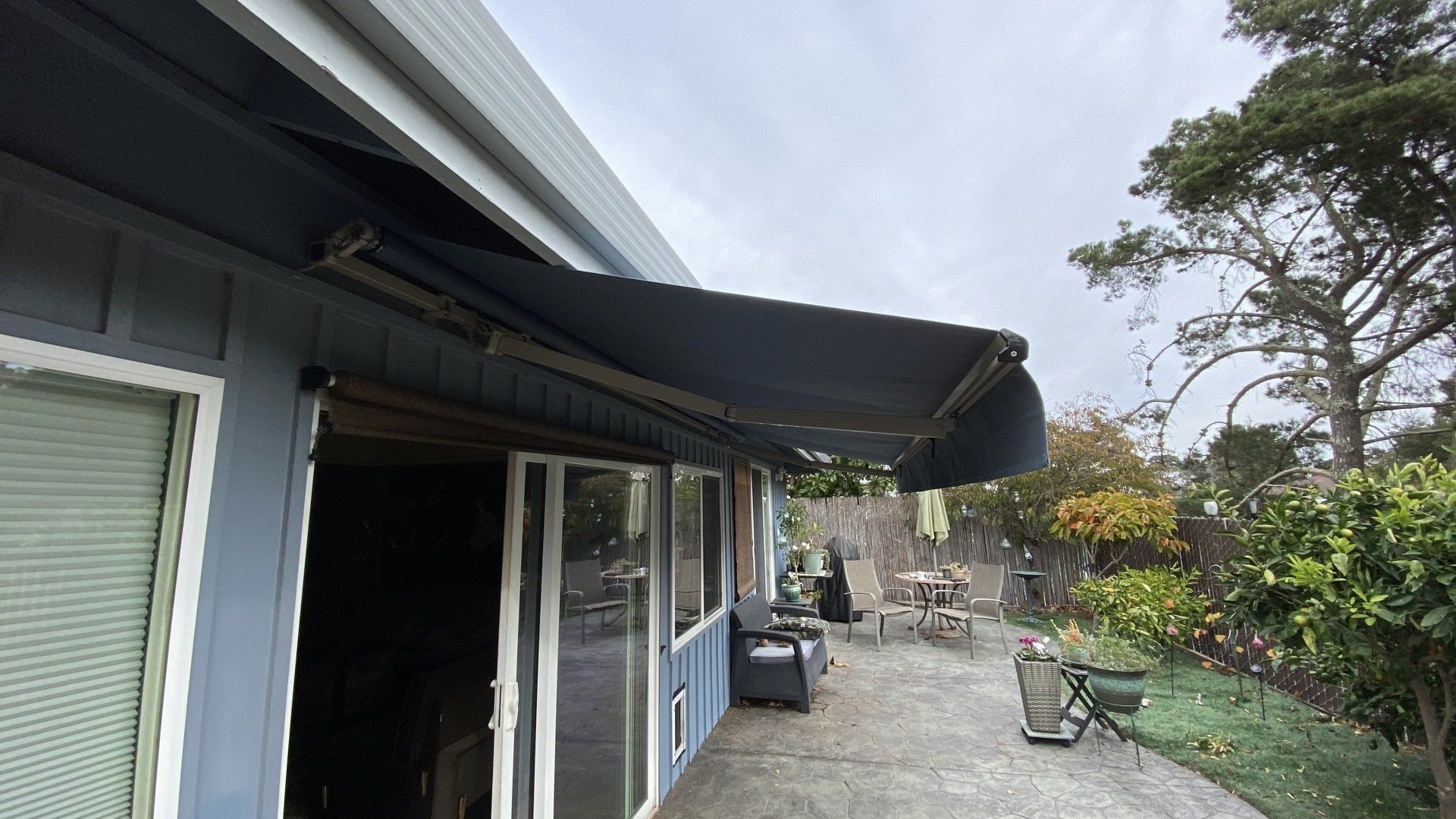 A blue house with a black awning on the side of it.