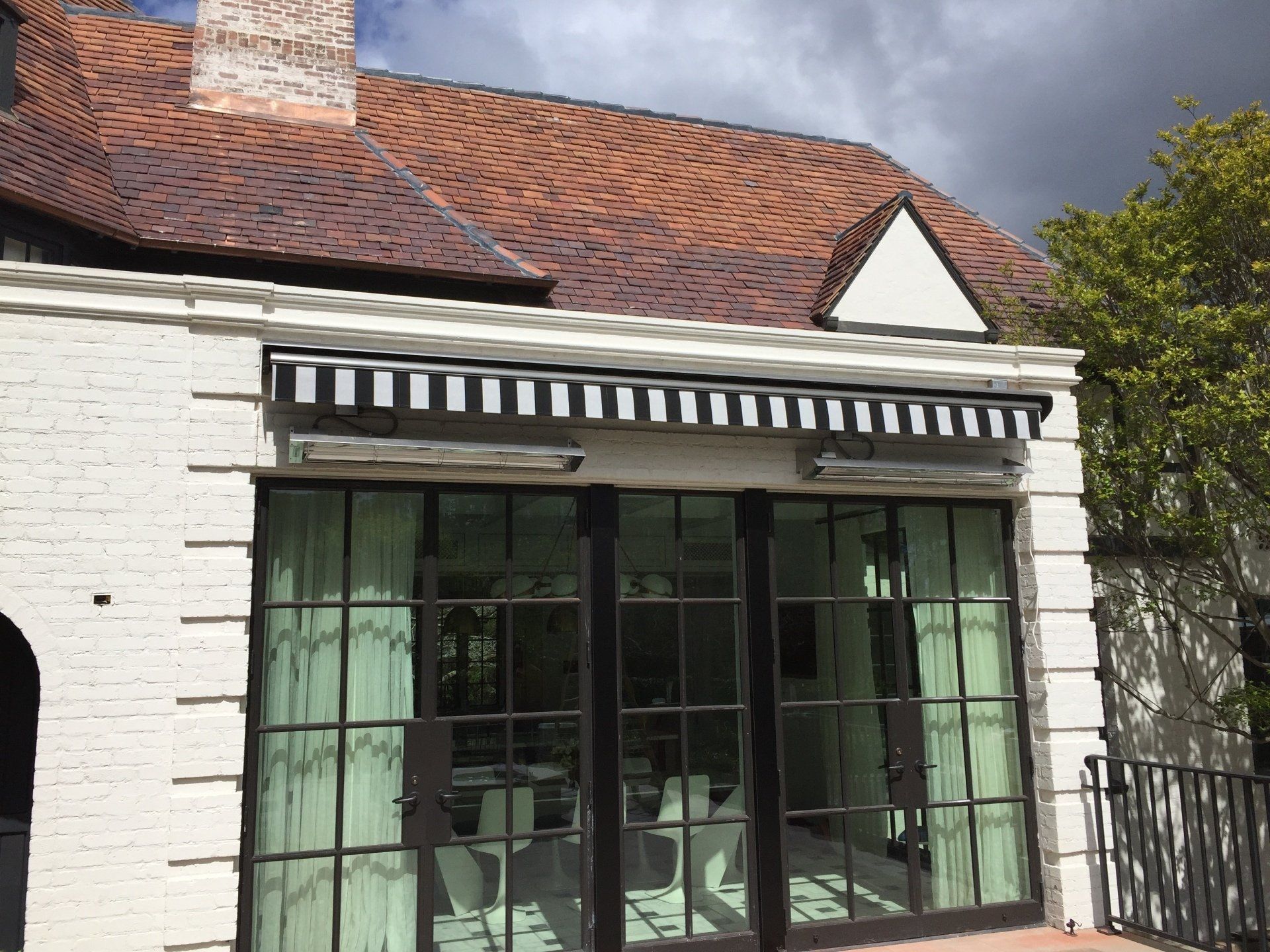 A white house with a black awning on the side of it.
