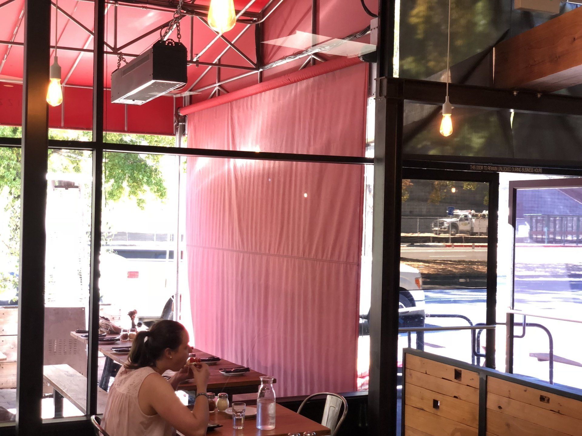 A woman is sitting at a table in a restaurant with a pink awning.