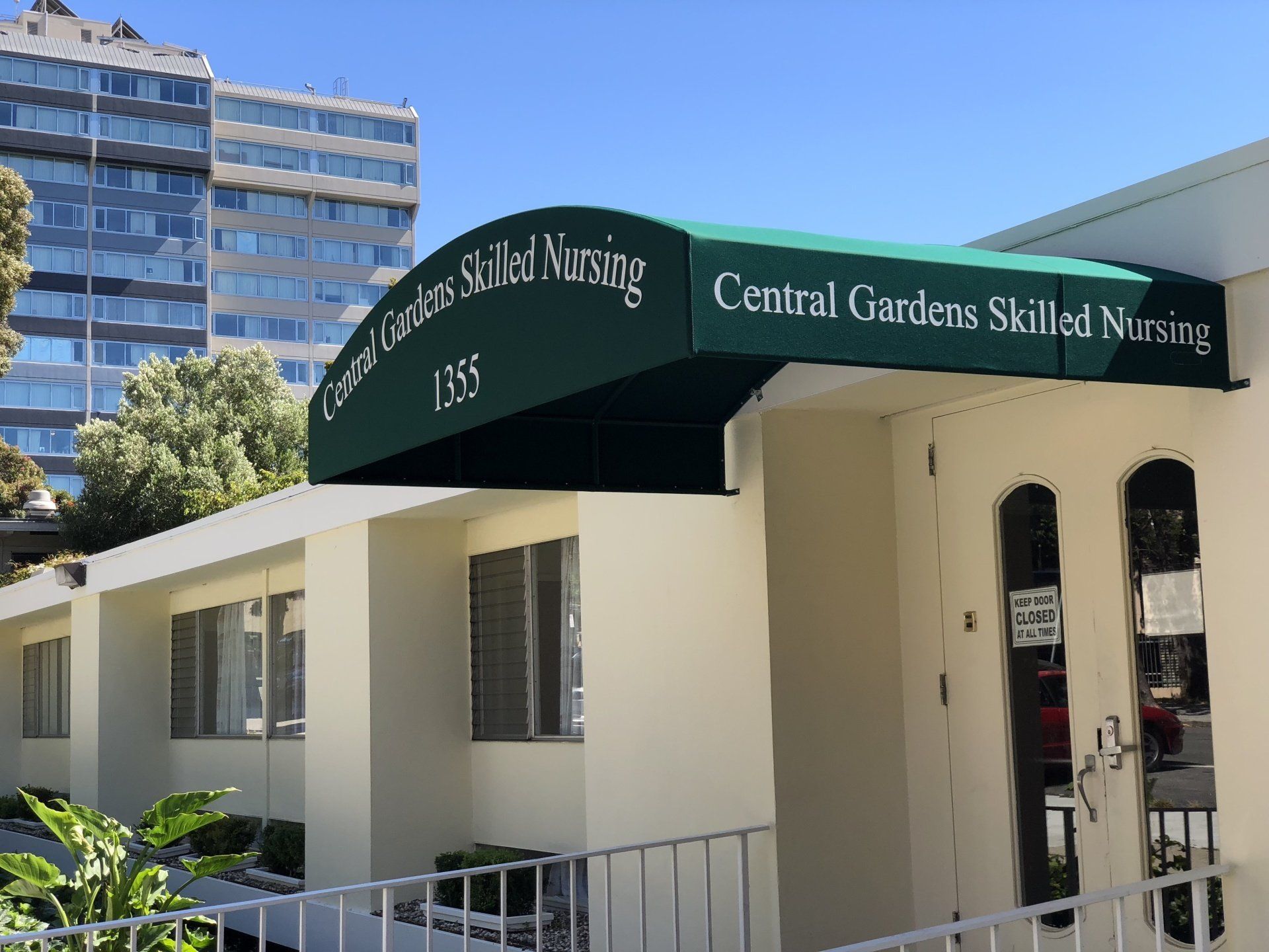 A building with a green awning that says central gardens skilled nursing