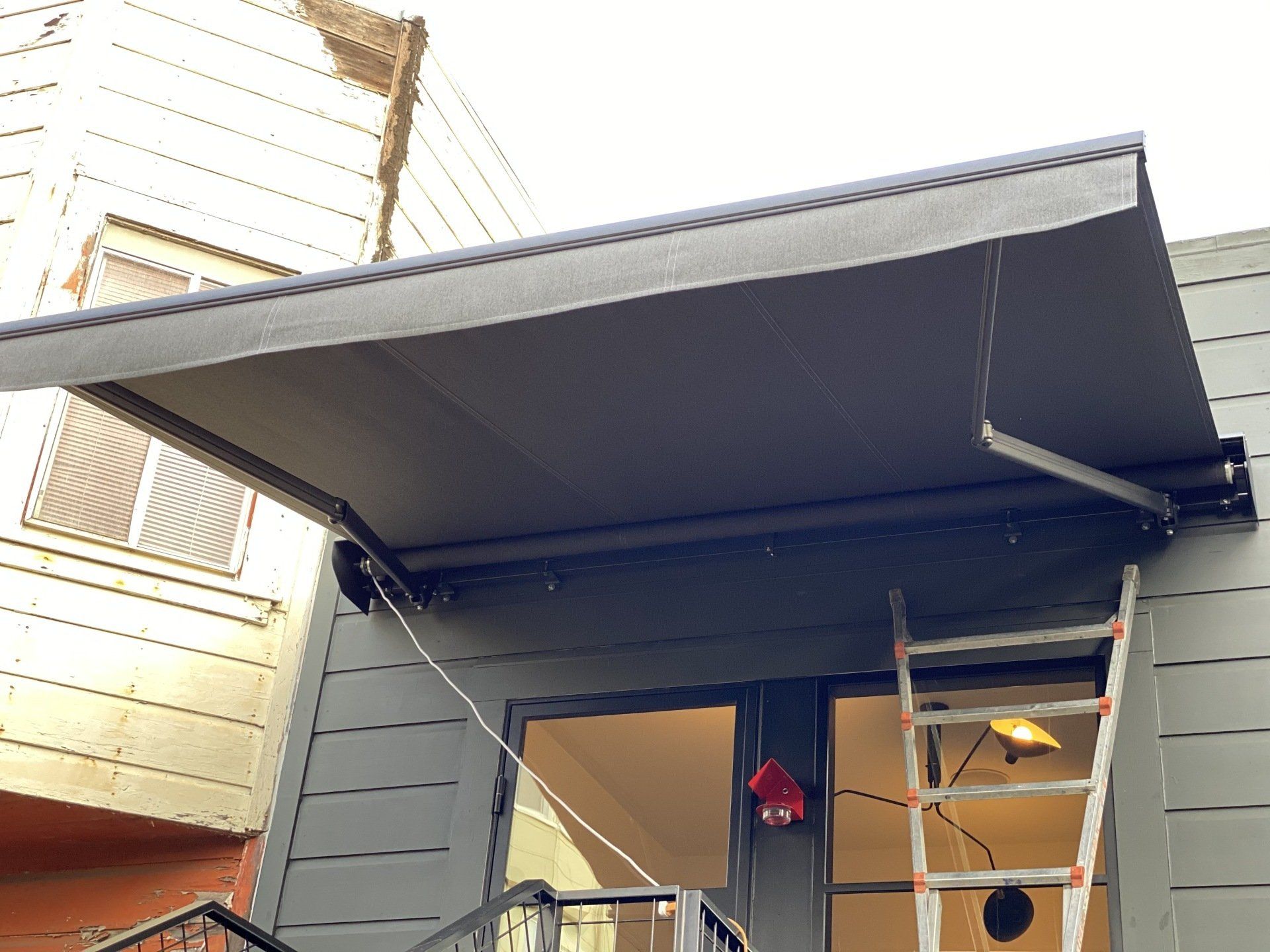 A black awning is hanging from the side of a building.