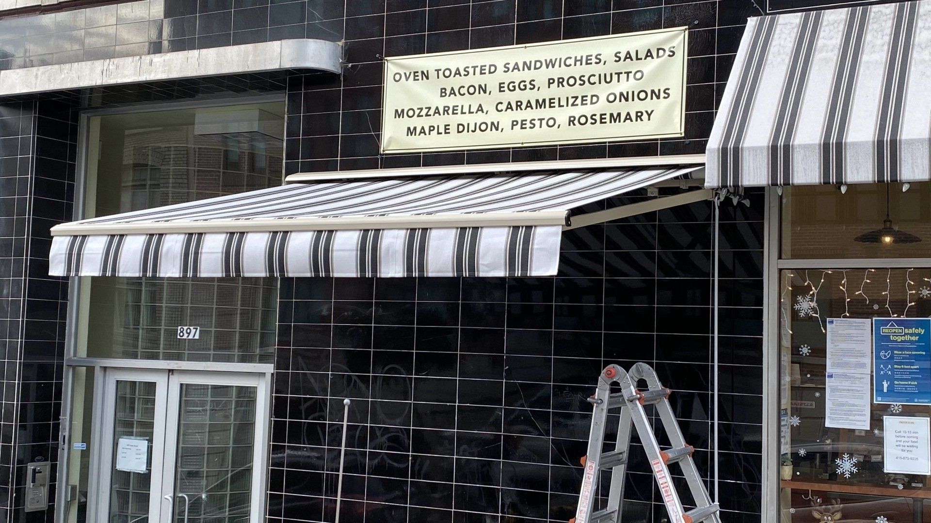 A ladder is sitting under an awning on the side of a building.