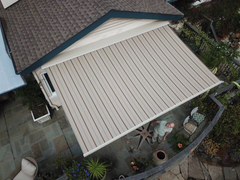 An aerial view of a man sitting under an awning on a patio.