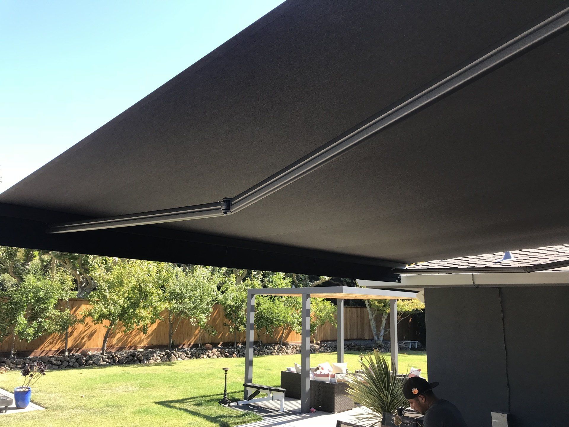 A person is standing under an awning in a backyard
