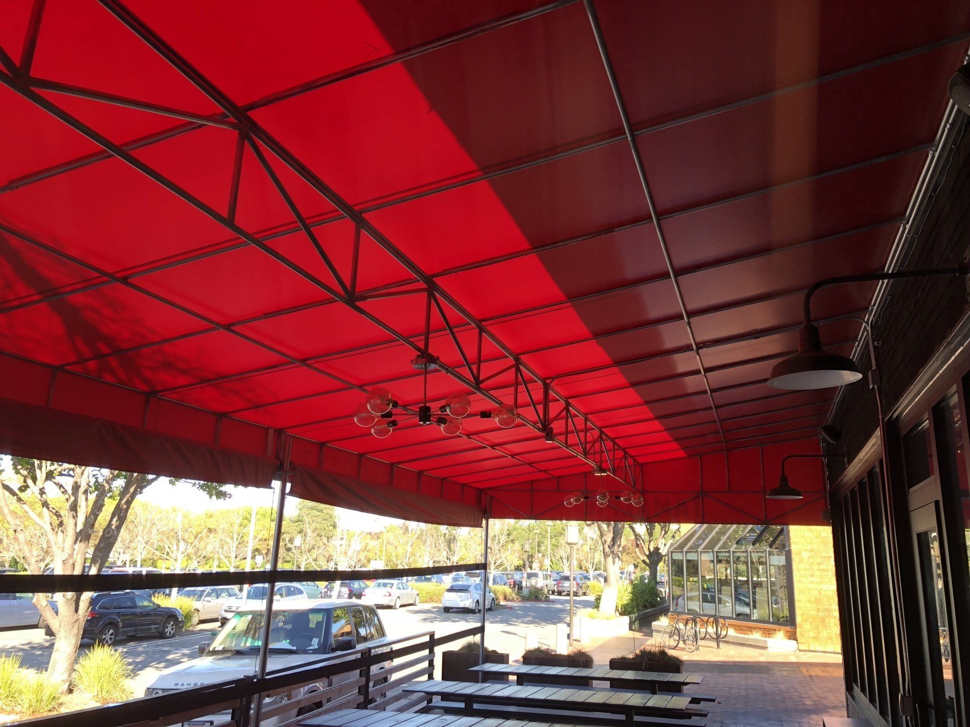 A red awning over a patio with tables and chairs
