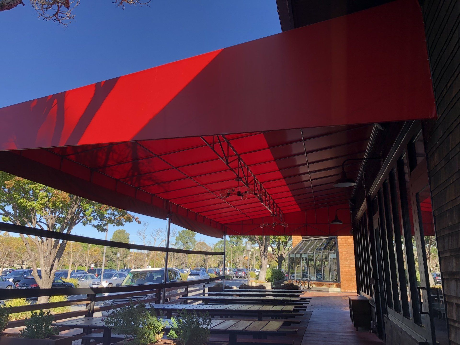 A red awning over a patio with tables and chairs