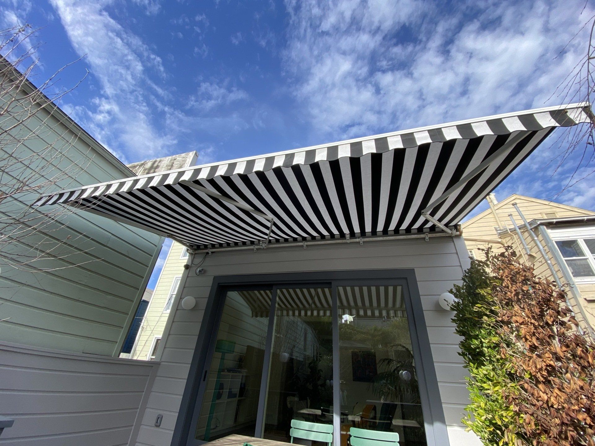 A black and white striped awning is on the side of a house.