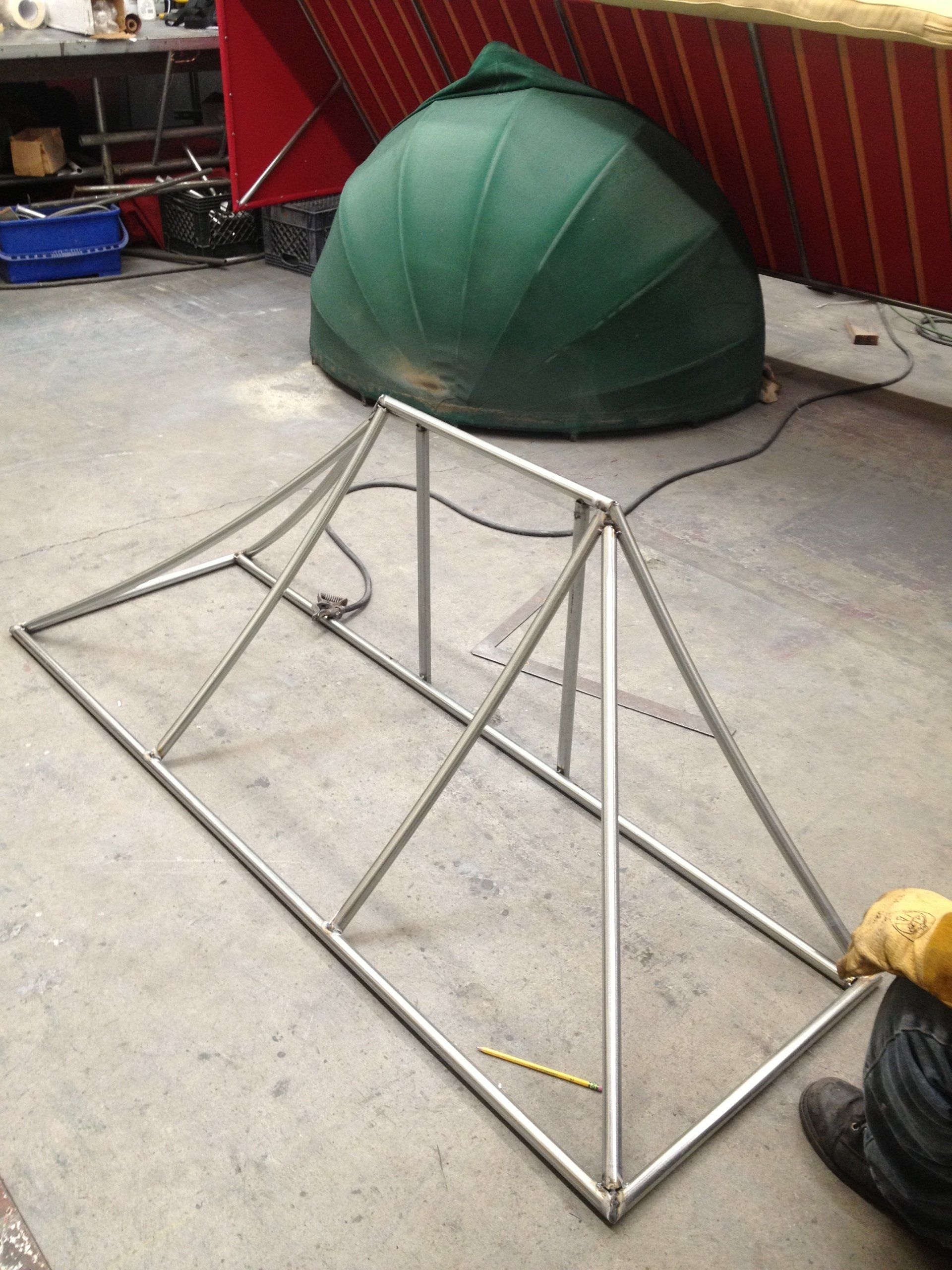 A metal frame is sitting on the floor next to a green dome