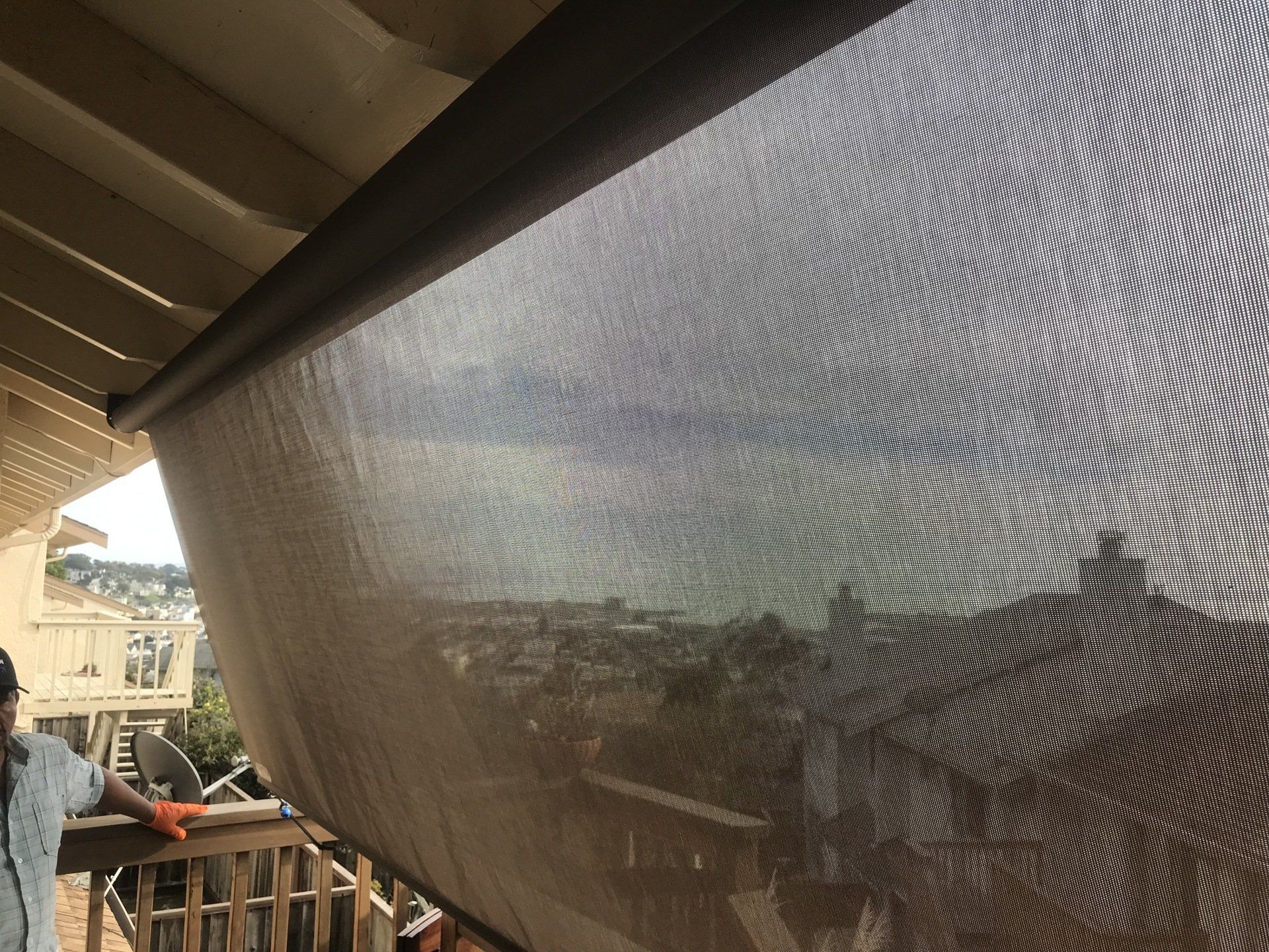 A person is standing on a balcony looking out over a city.