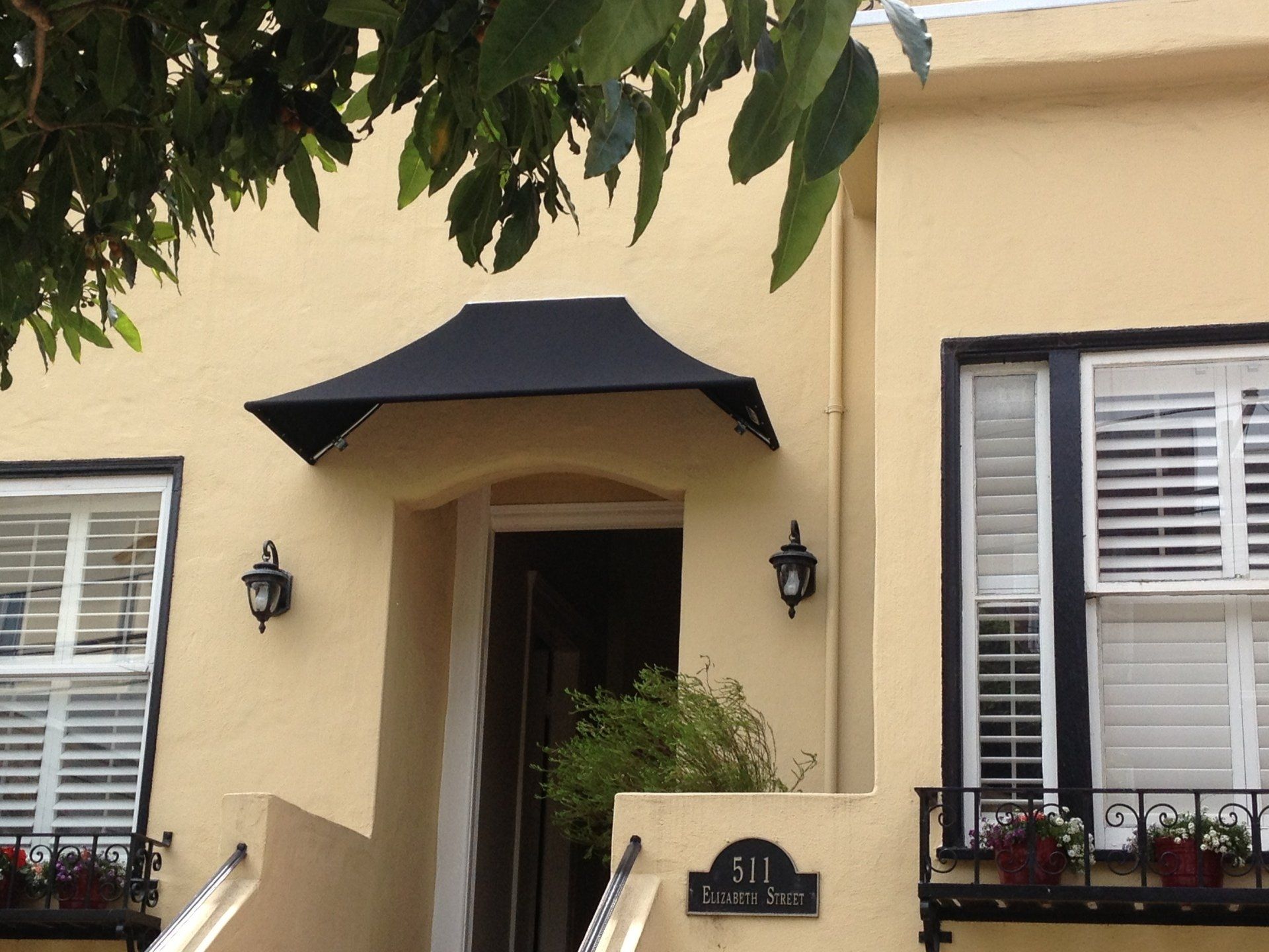 A yellow house with a black awning over the front door