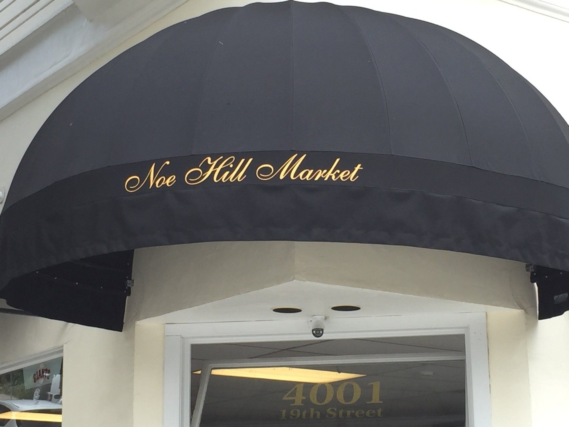 A black awning that says noe hill market on it