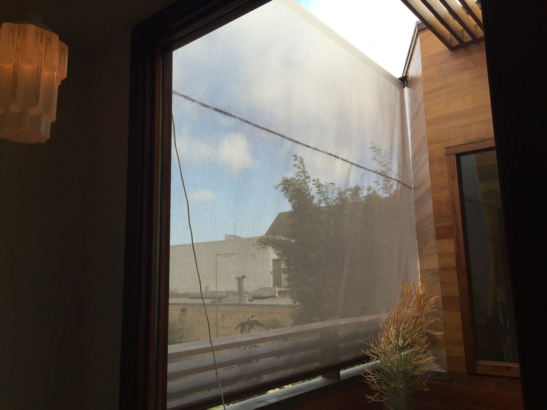 A window with a blind on it and a view of a city