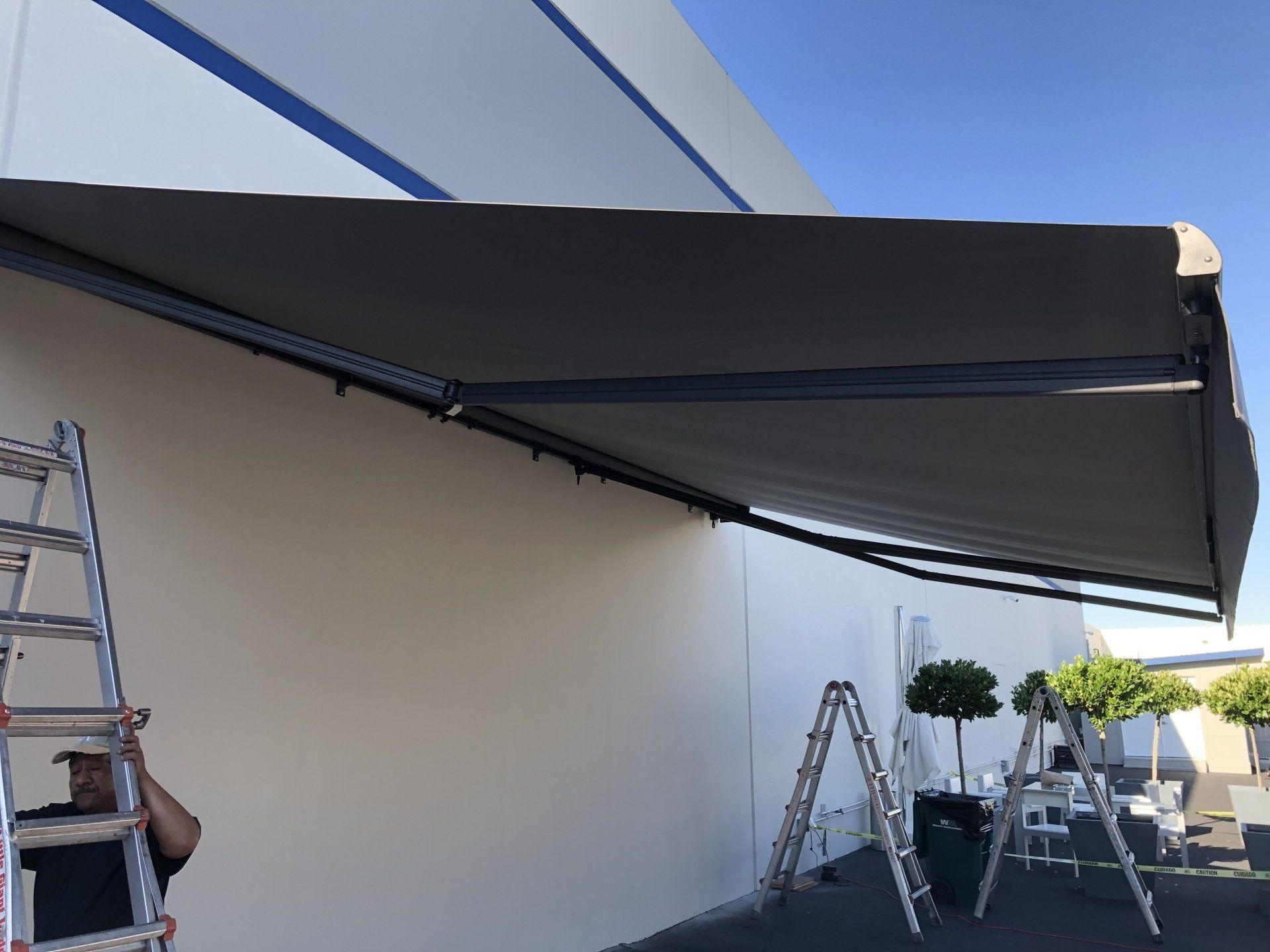 A man is standing on a ladder under an awning