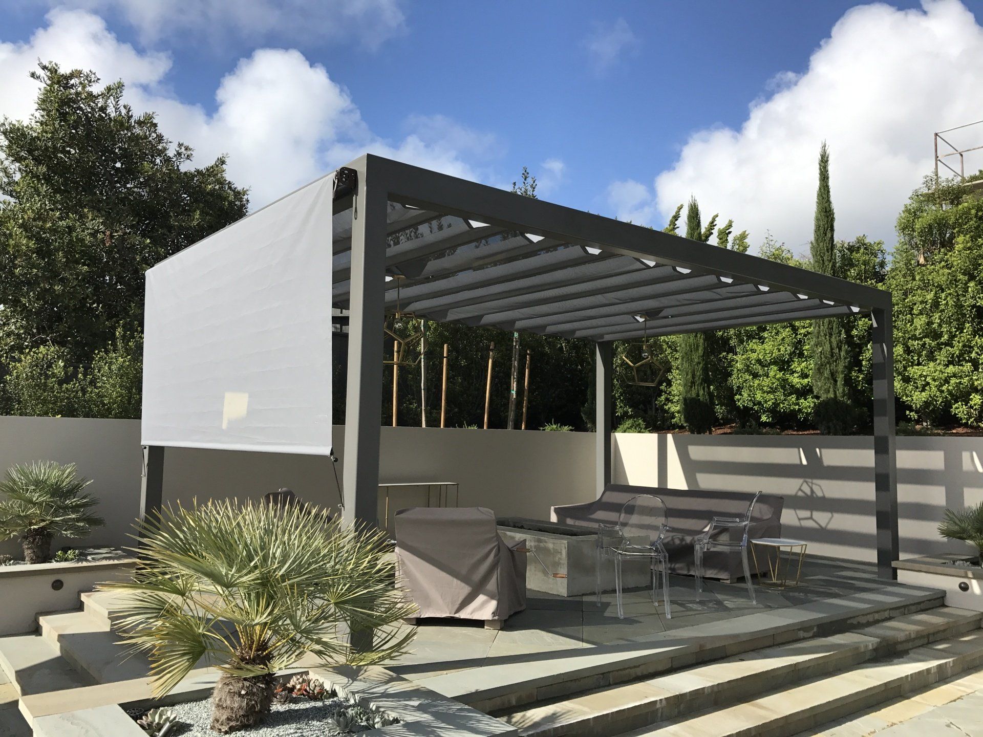 A patio with a pergola and a table and chairs underneath it