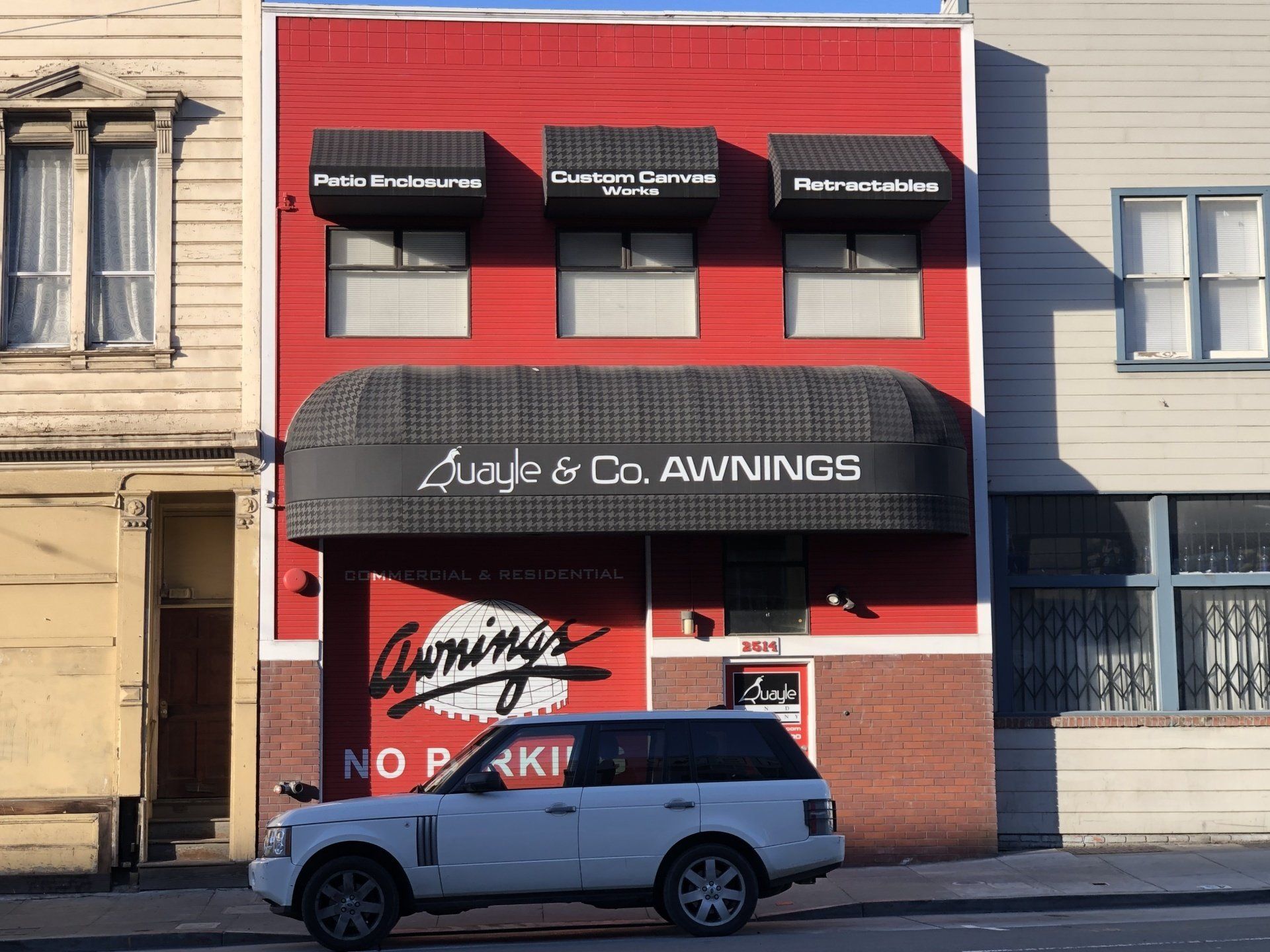 A white suv is parked in front of a building that says cummings awnings