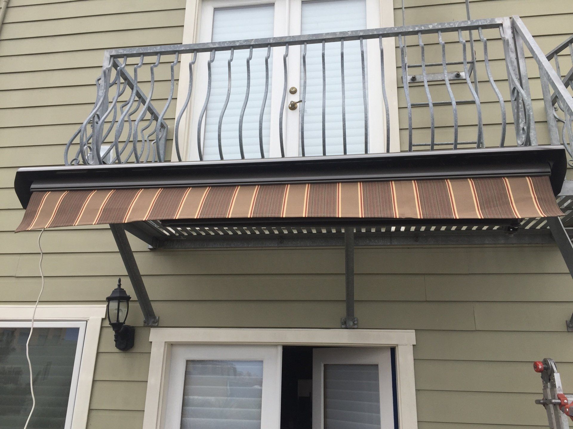 A balcony on the side of a house with an awning over it
