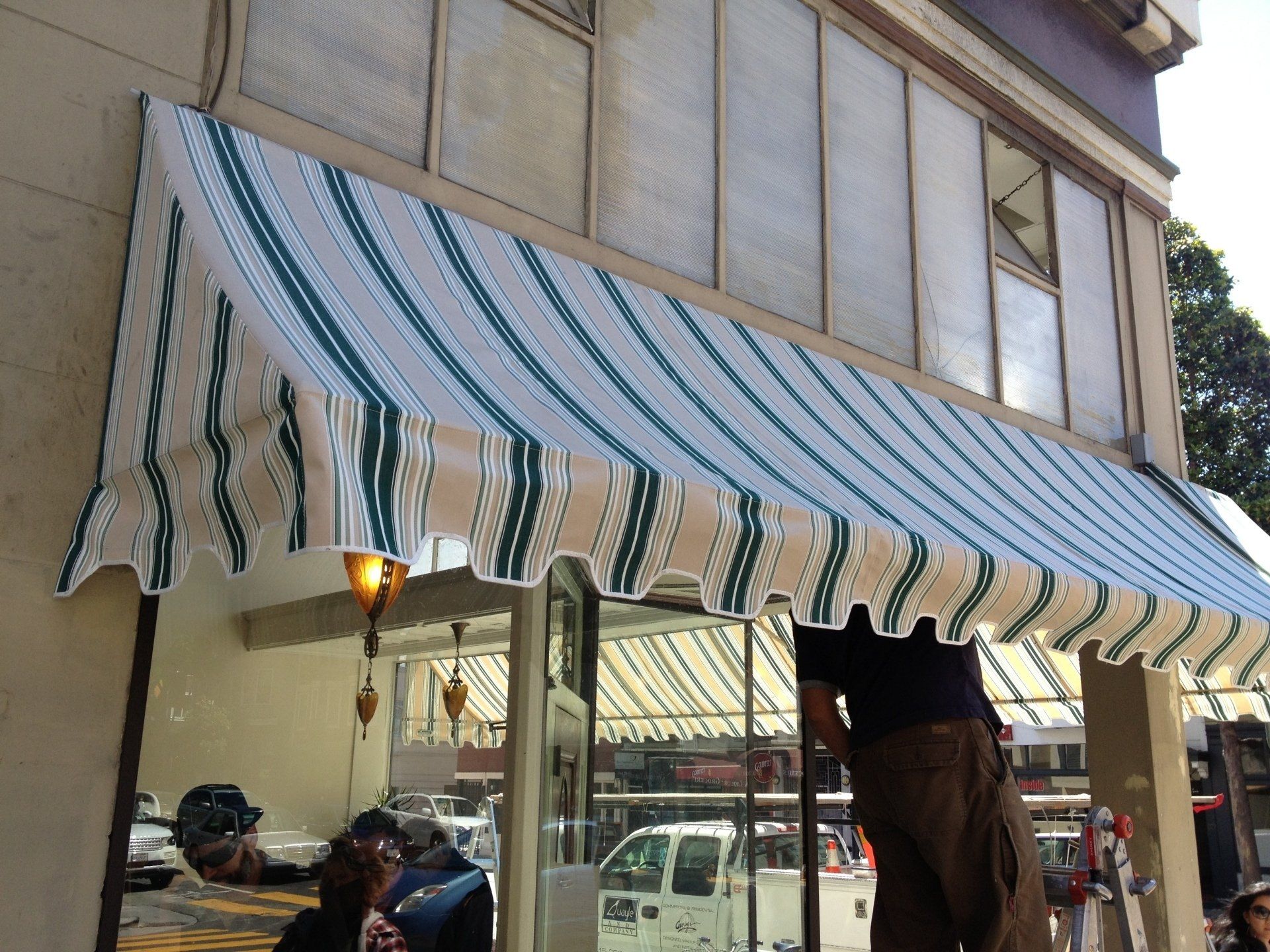 A man is standing under a striped awning on the side of a building