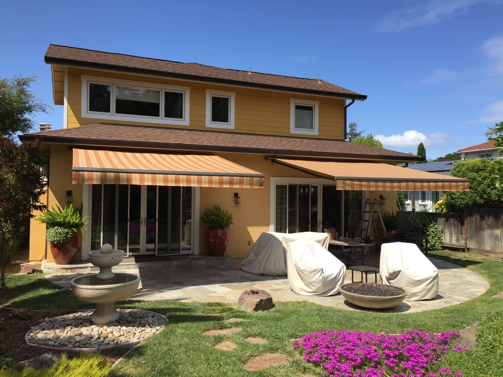 A large yellow house with a striped awning on the roof.