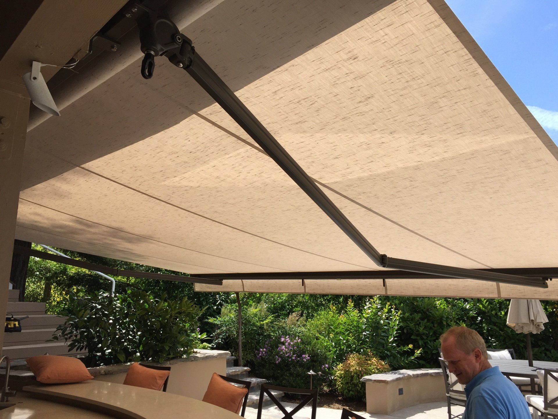 A man sits under an awning on a patio