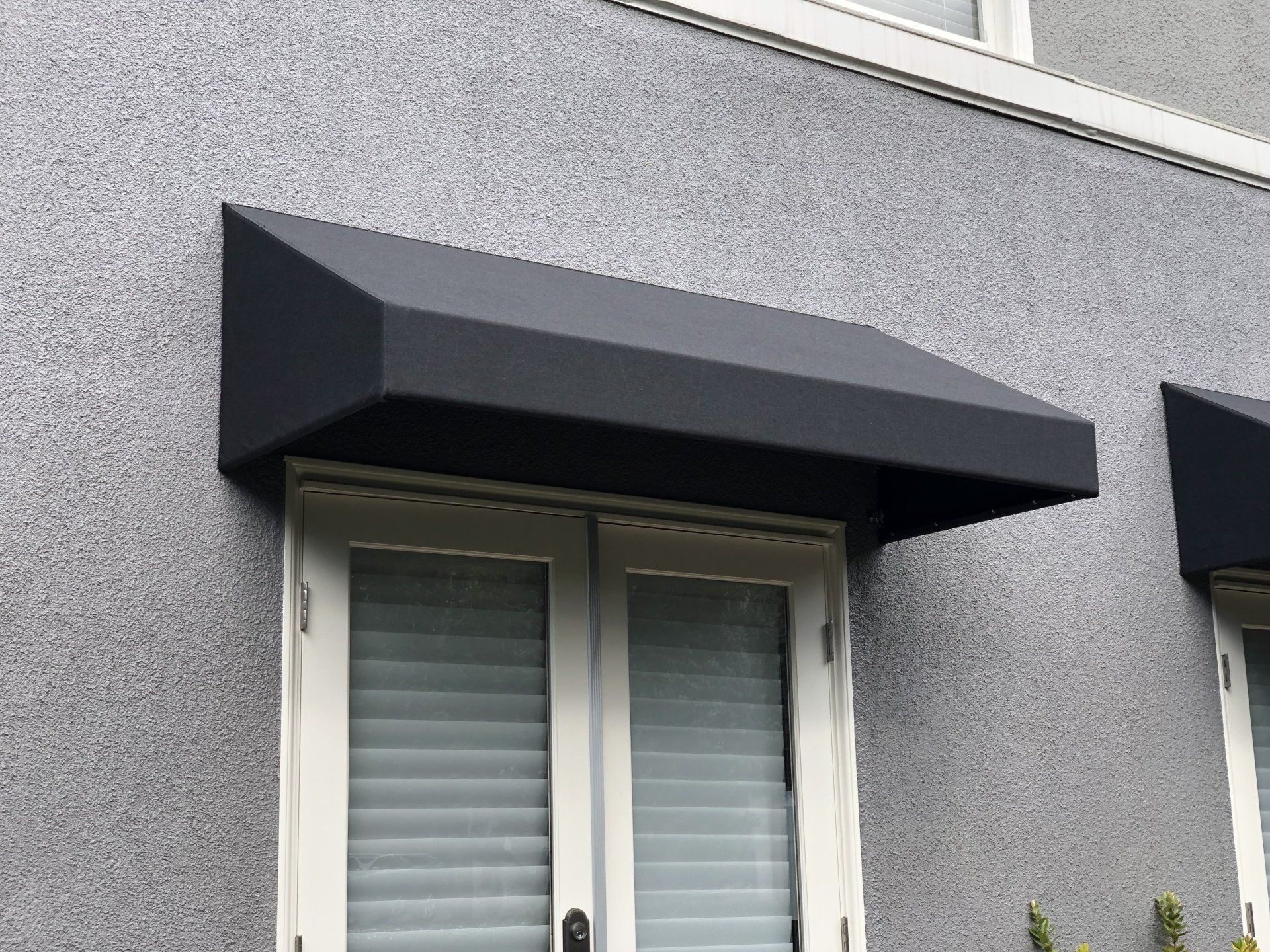 A window with a black awning over it on the side of a building.