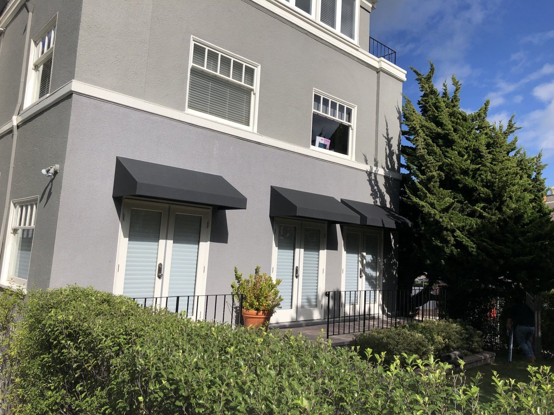 A gray building with black awnings on the windows