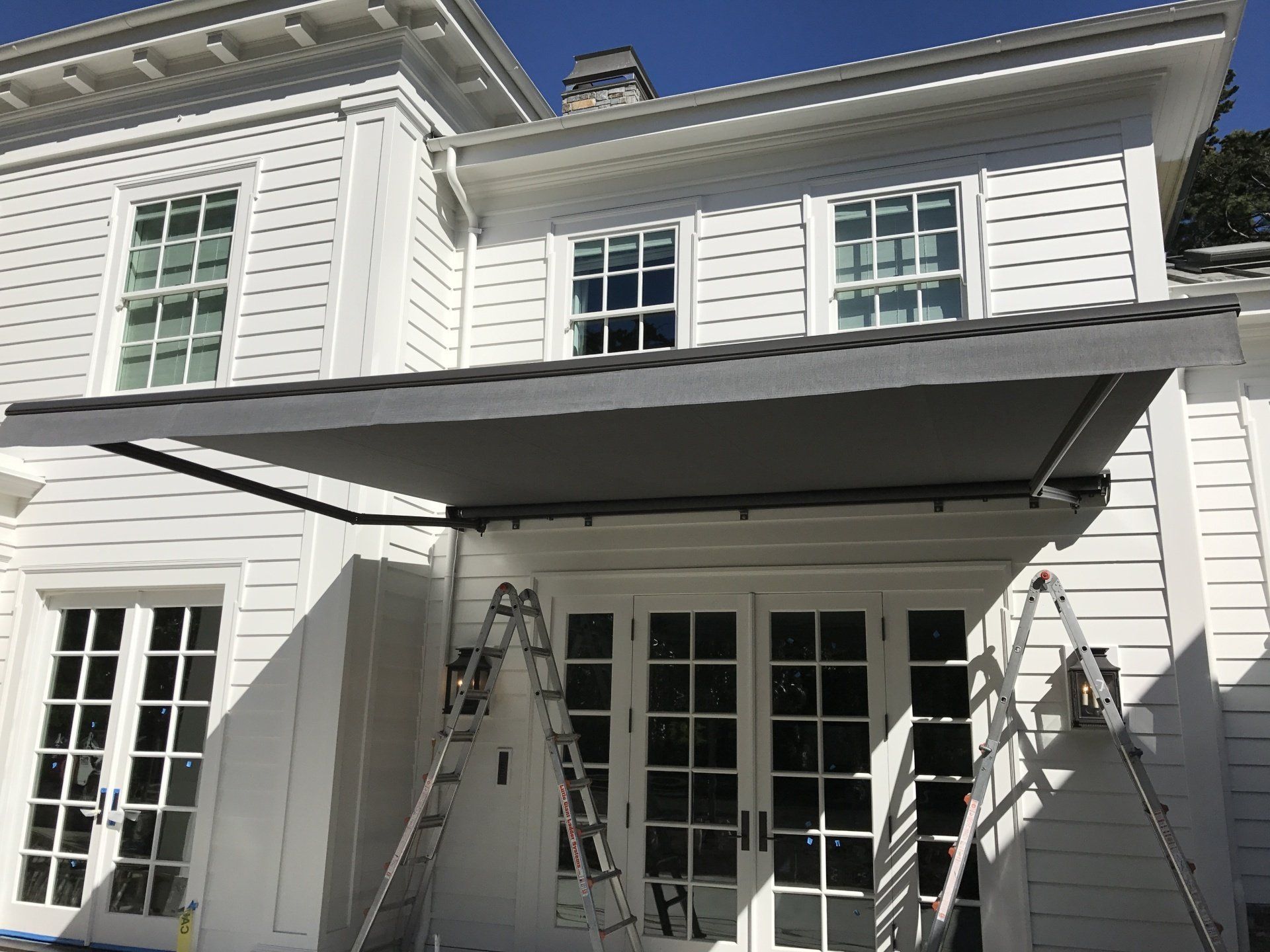 A white house with a gray awning on the side of it.