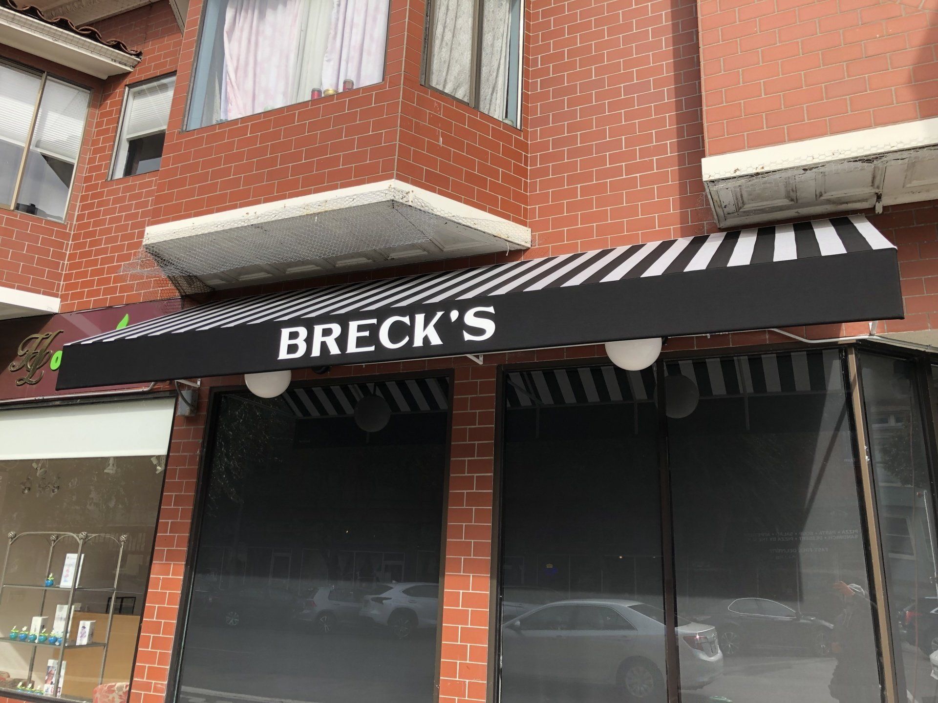 A brick building with a black awning that says breck 's