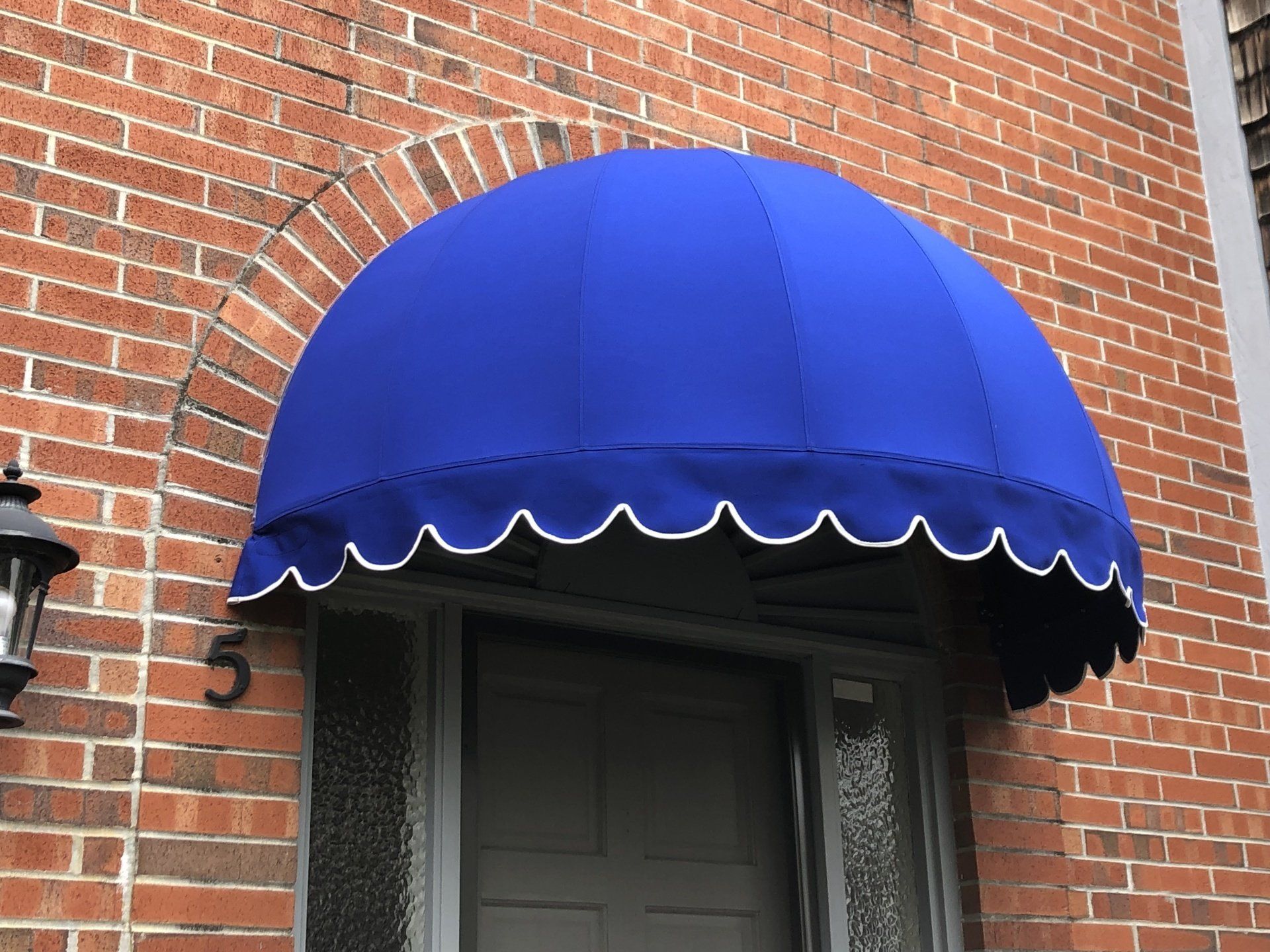 A blue awning over a door on a brick building