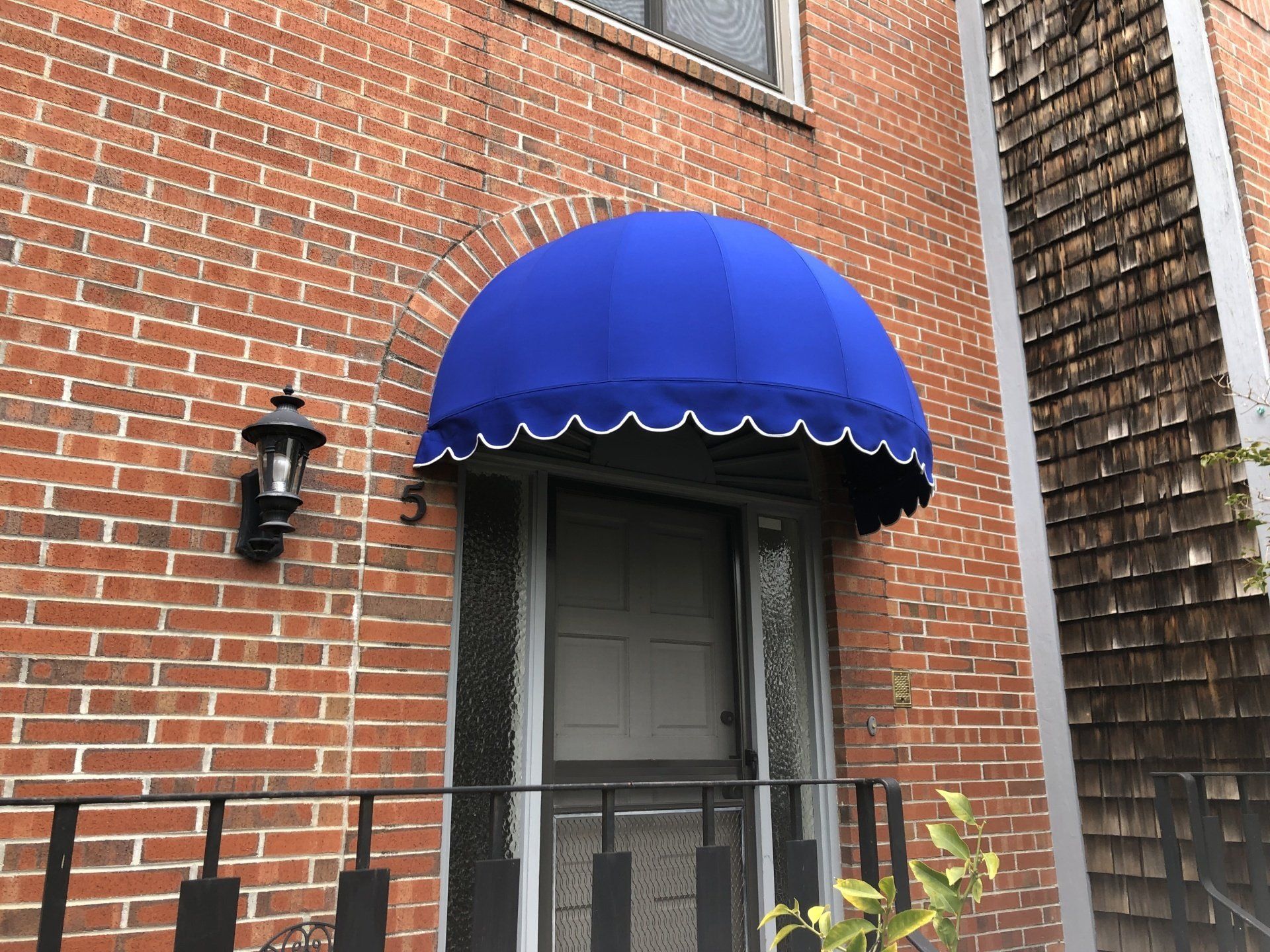 A blue awning is on the front door of a brick building.