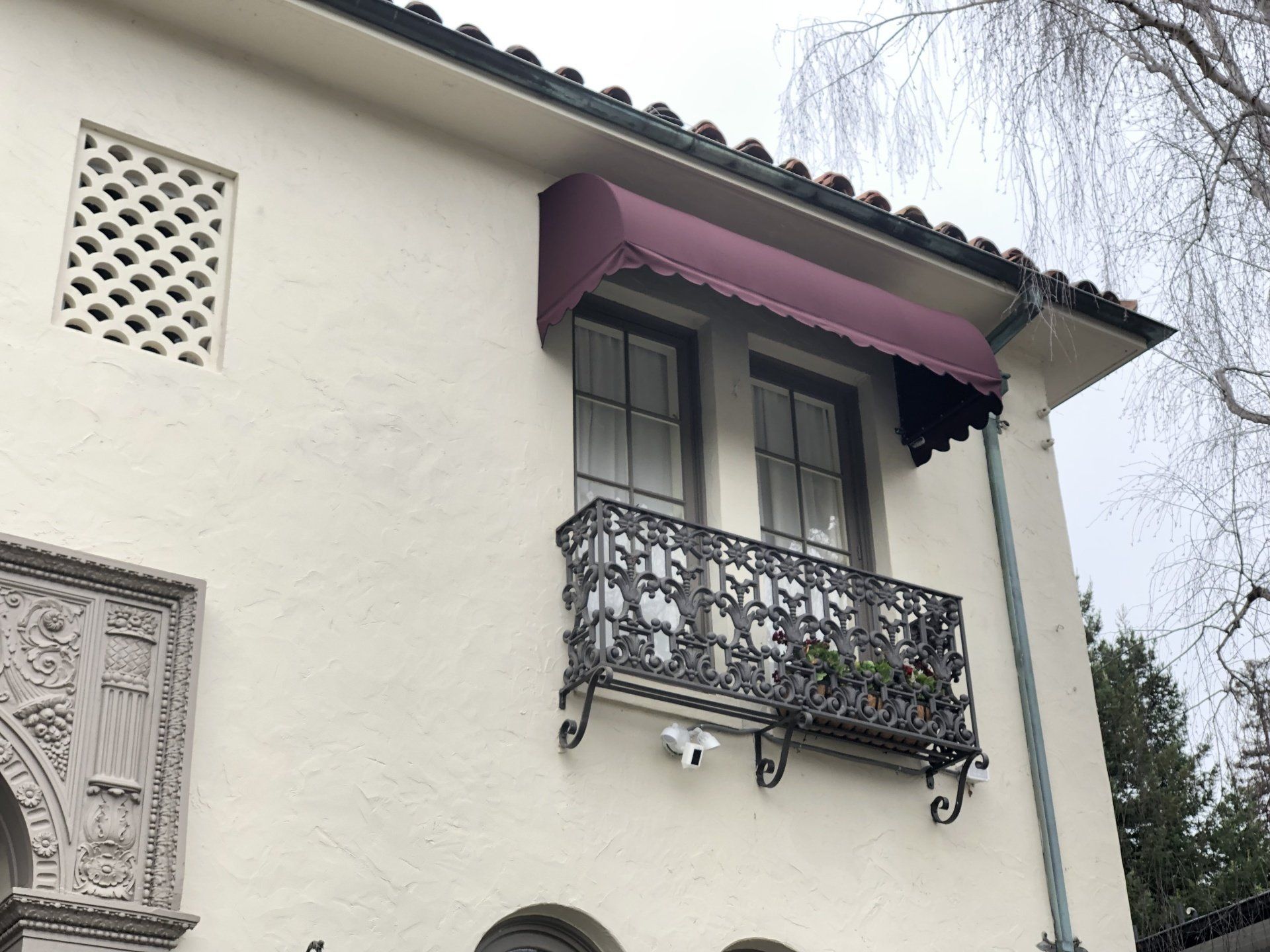 A white building with a balcony and a purple awning on it.
