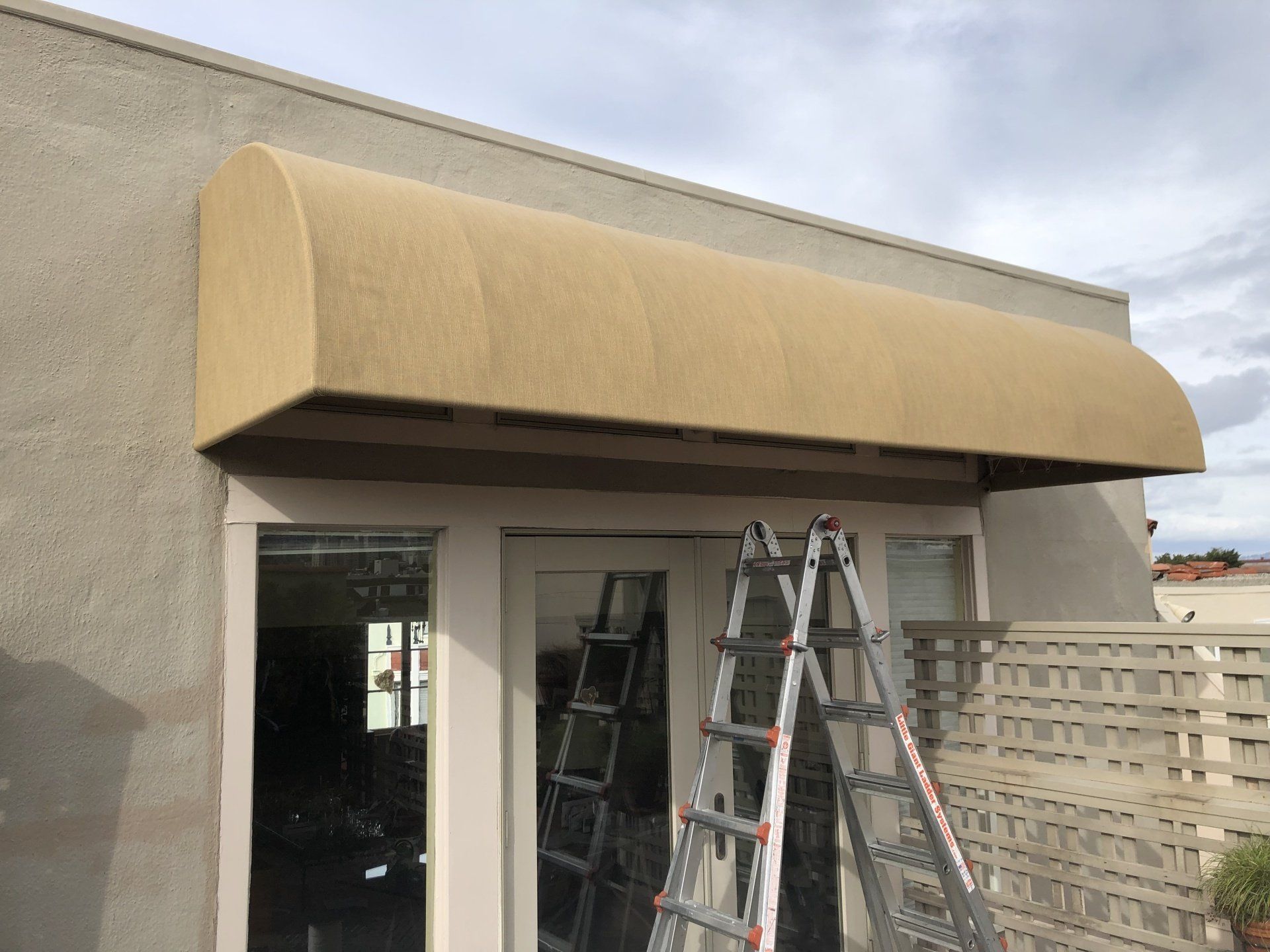 A ladder is sitting under a canopy on the side of a building.