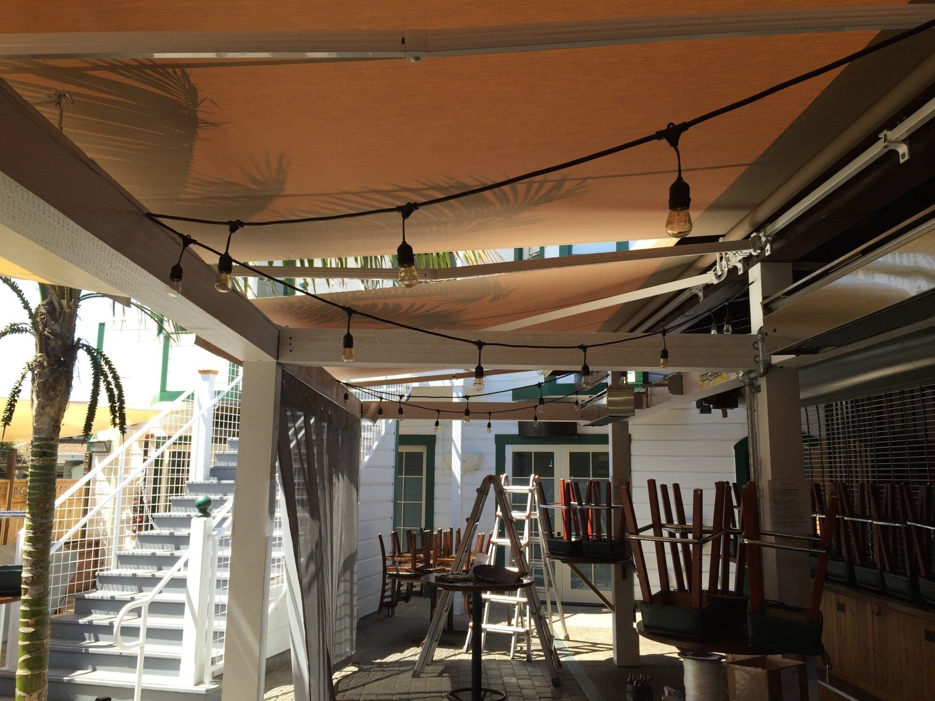 A patio with tables and chairs under an awning