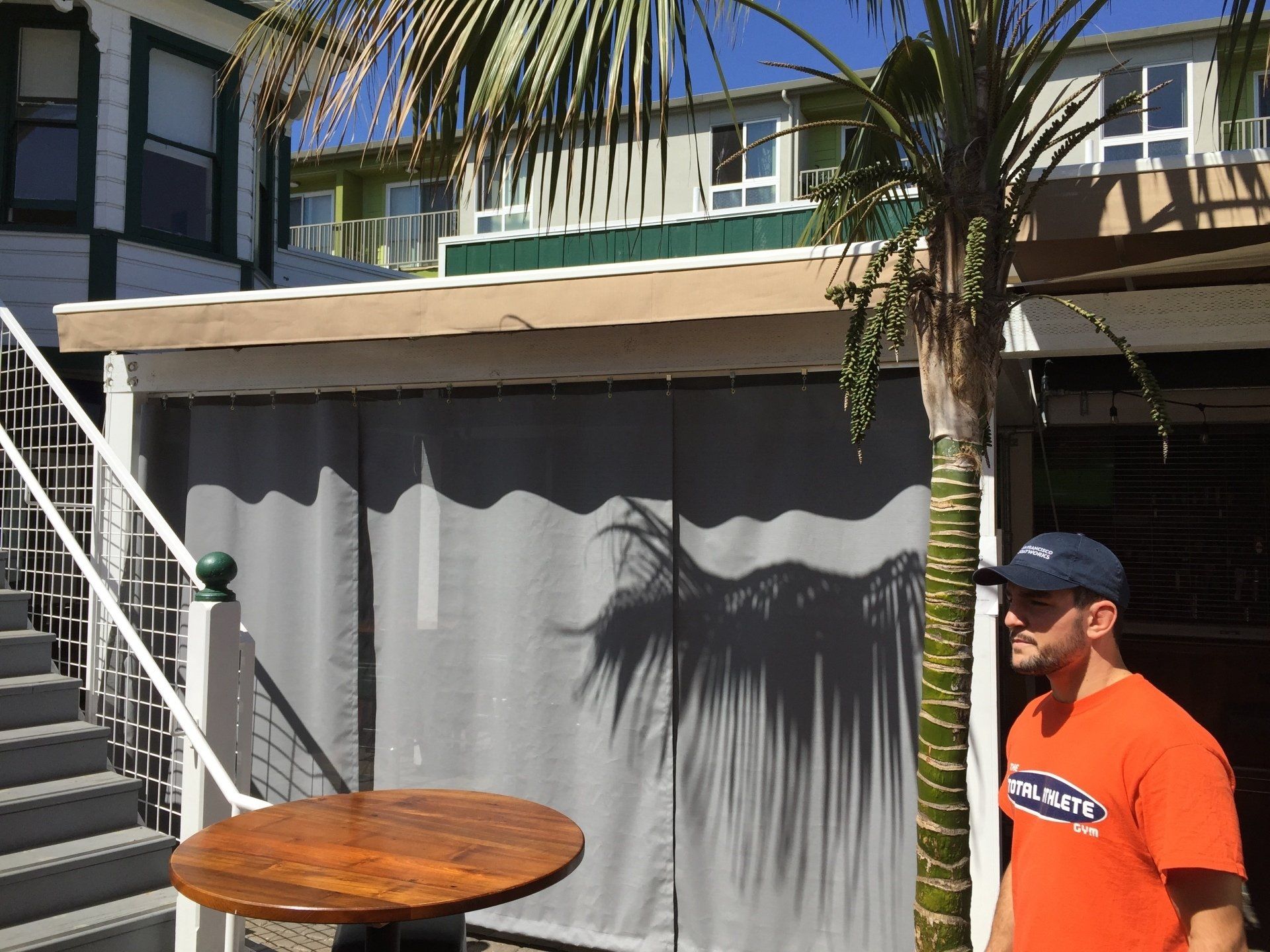 A man in an orange shirt is standing in front of a building