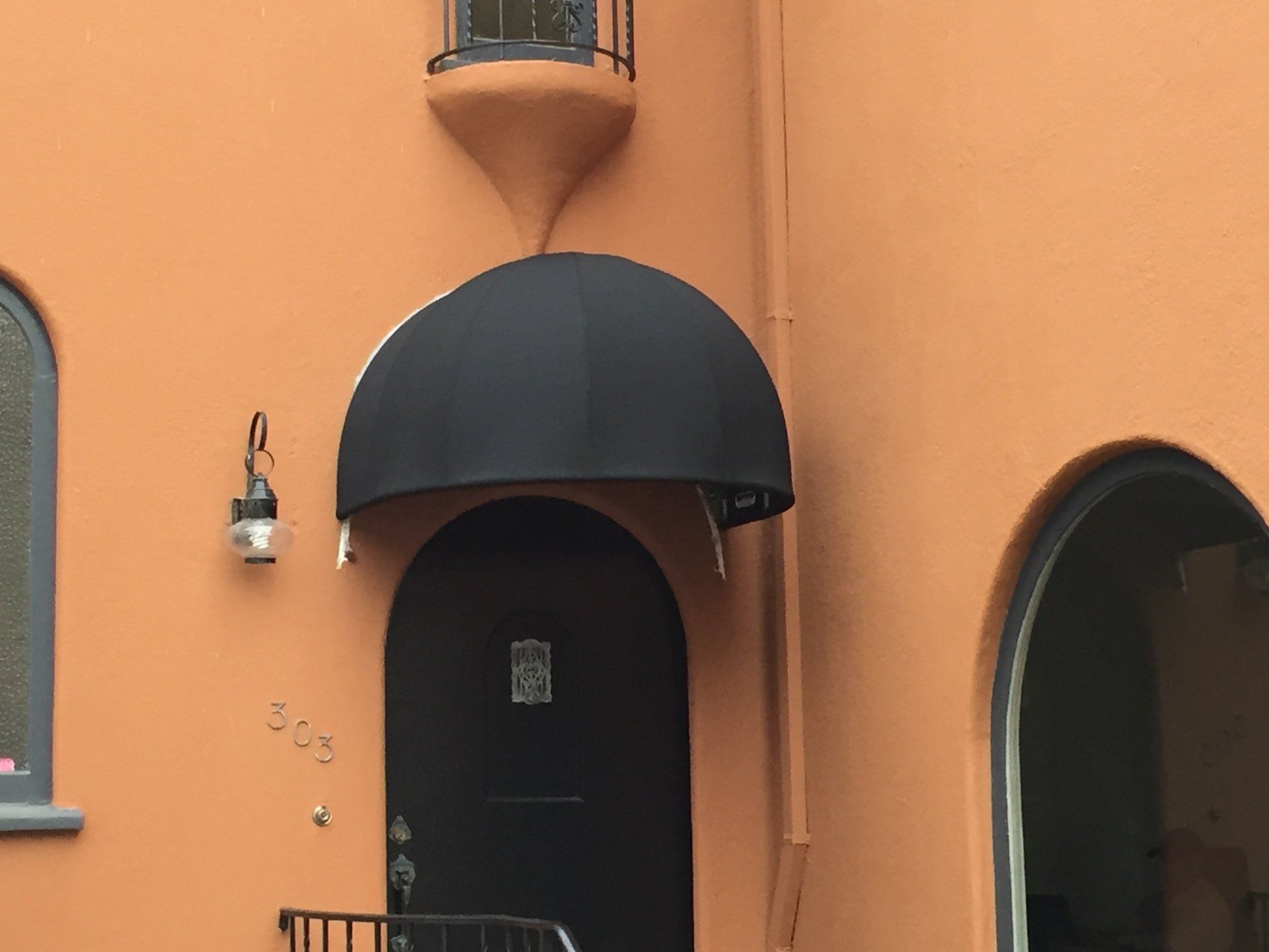 The front door of a building with a black awning over it.