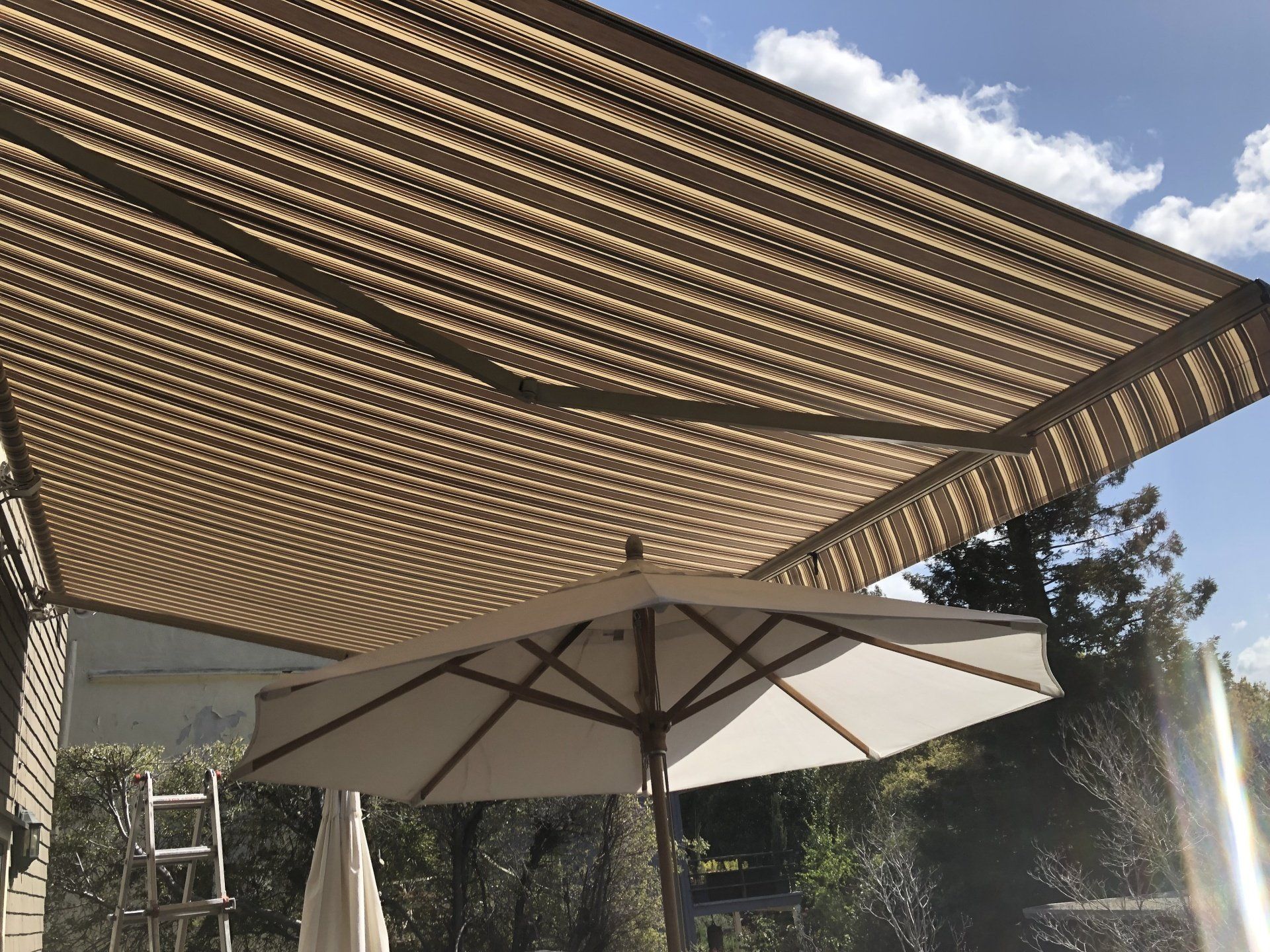 A large umbrella is under an awning on a patio.