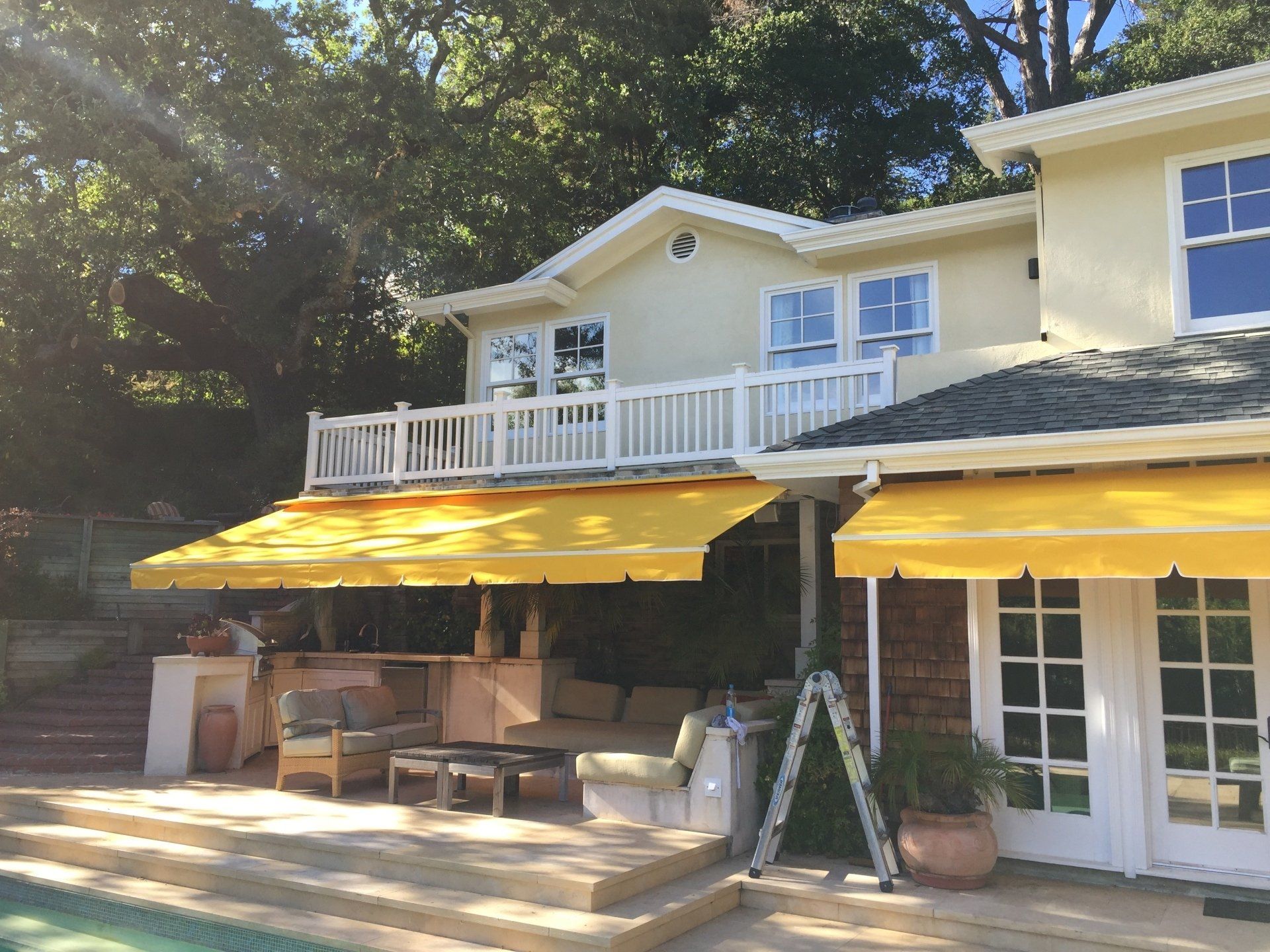 A house with a yellow awning and a ladder in front of it
