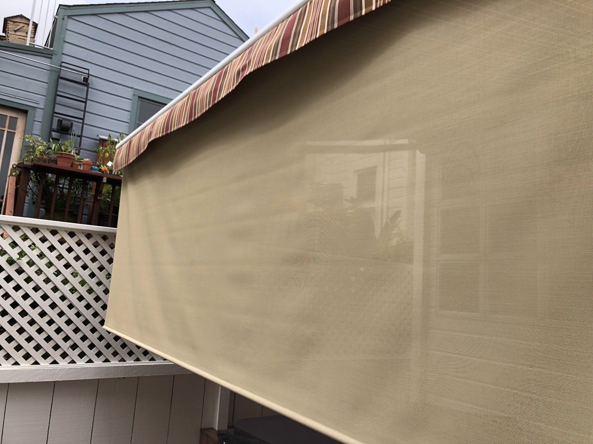 A beige awning is hanging from the side of a building.