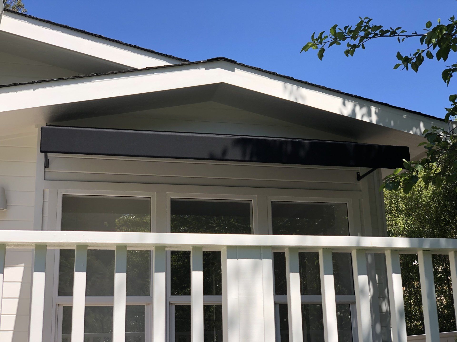A white house with a black awning on the roof