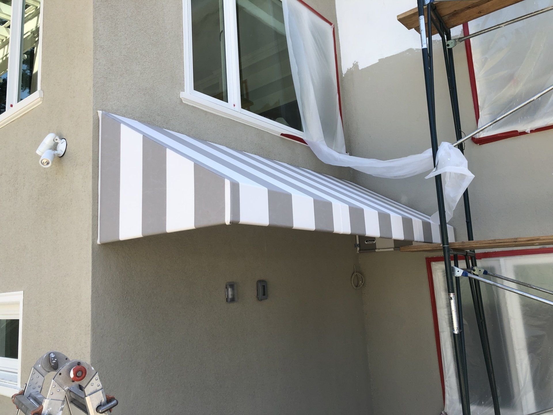 A striped awning is being installed on the side of a building