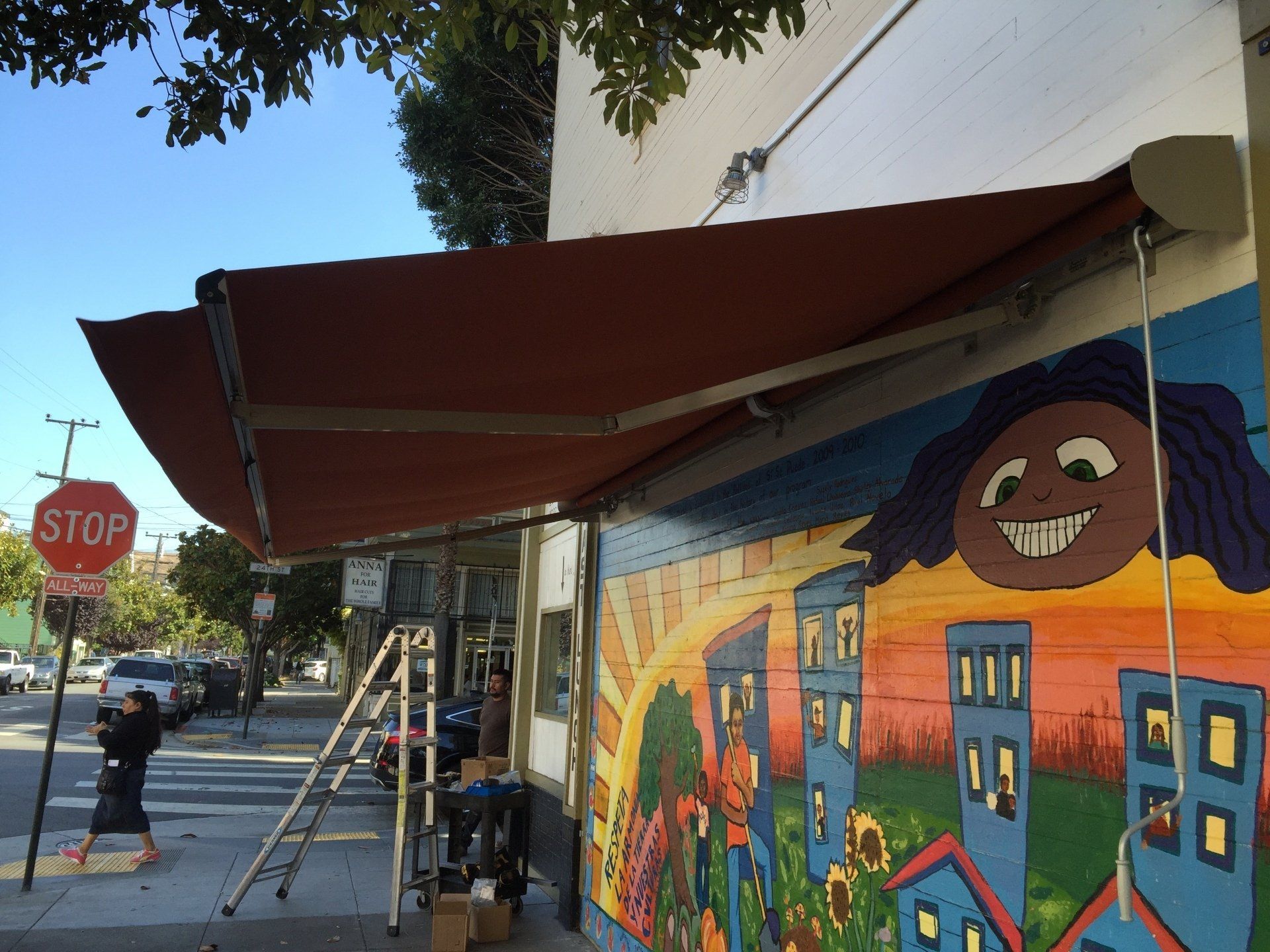 A stop sign is in front of a building with a mural on it